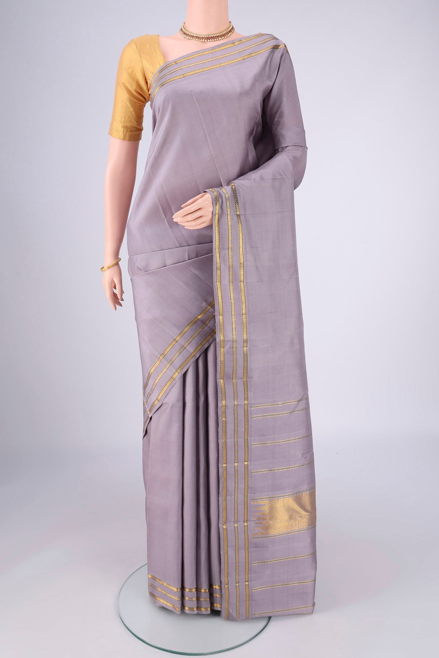Lilac Kanchipuram Silk Saree with Plain Body and Zari Border.  displayed on a mannequin