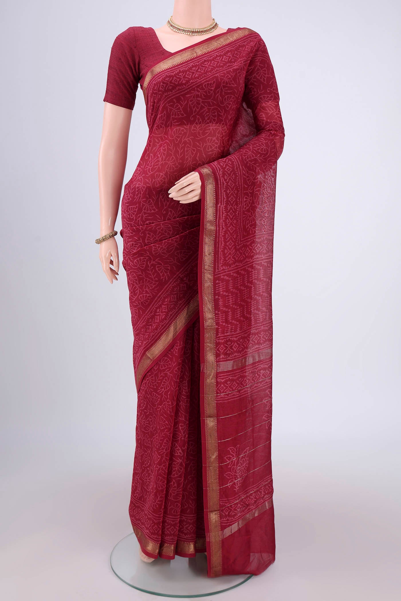 Maroon Maheshwari Silk Cotton Saree with Printed design on the body and Zari Border.  displayed on a mannequin