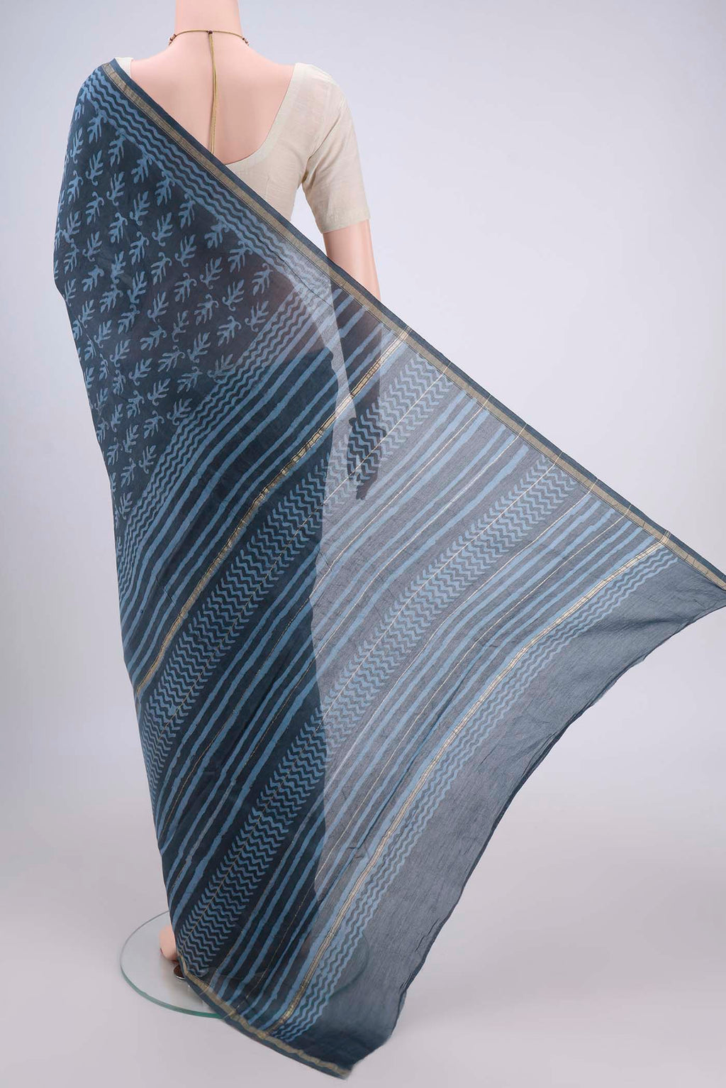 Flat view of Blue Grey Maheshwari Silk Cotton Saree with Batik Print on the body and Zari Border. 