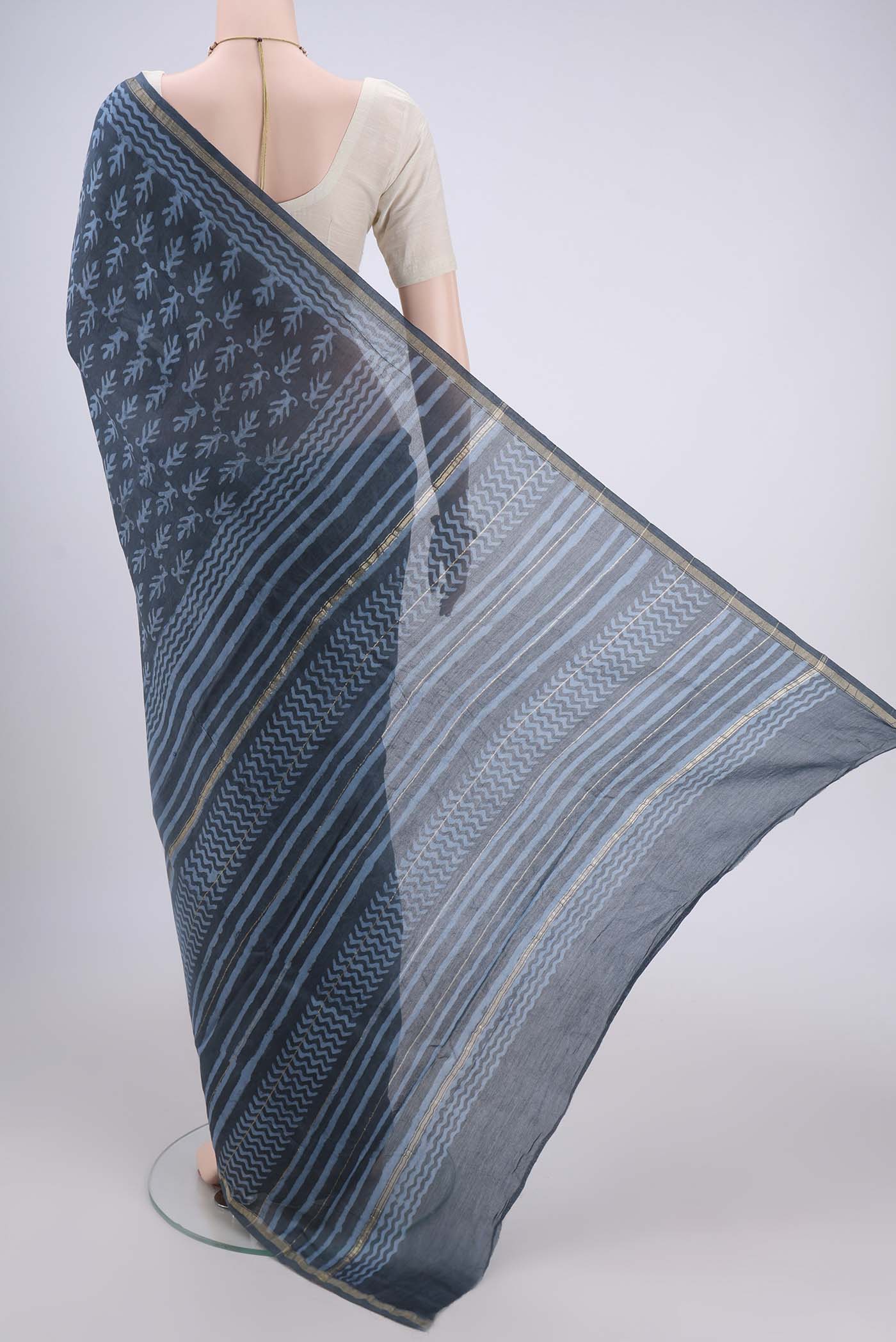 Flat view of Blue Grey Maheshwari Silk Cotton Saree with Batik Print on the body and Zari Border. 