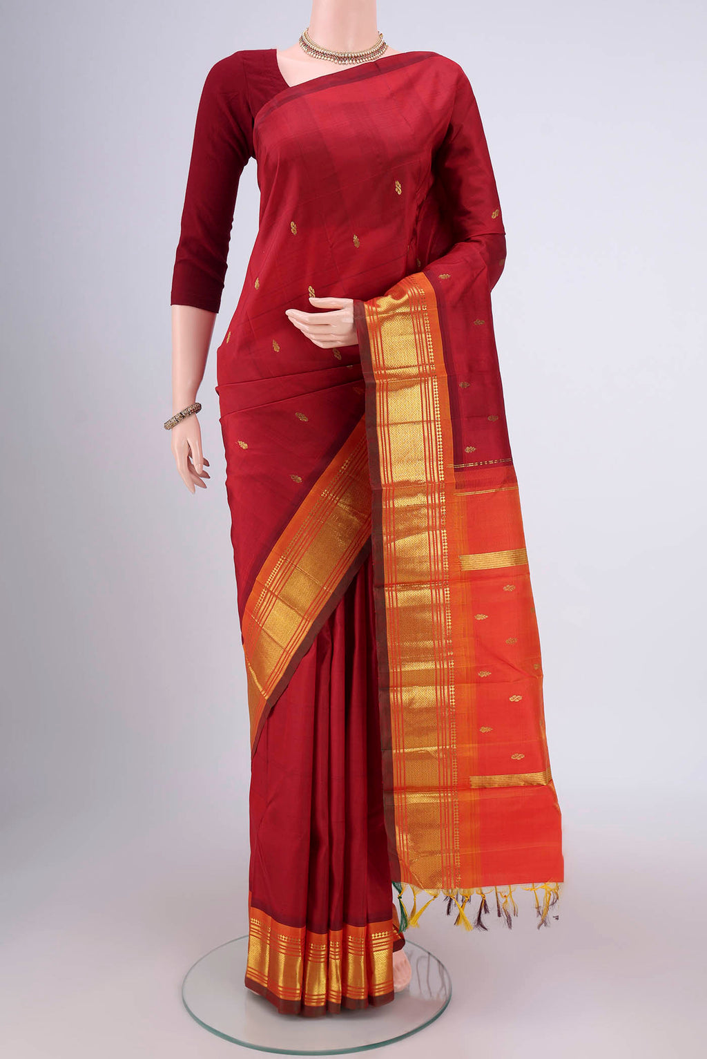 Maroon Kanjivaram Silk Saree with Zari Butta on the body and One Side Border.  displayed on a mannequin
