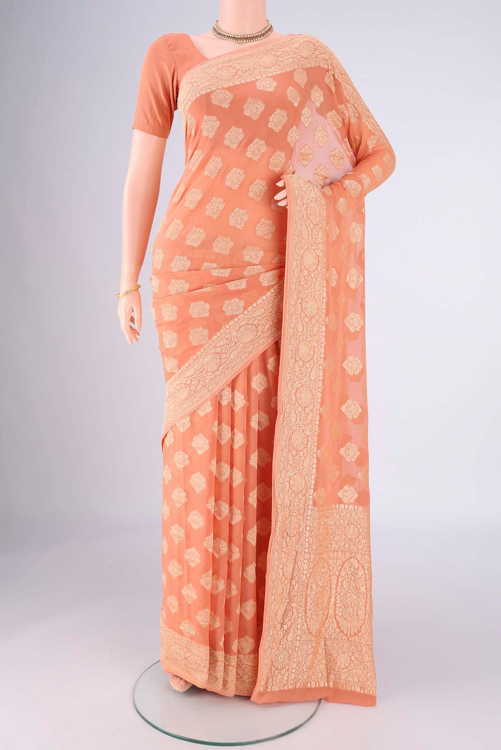 Peach Banarasi Georgette Saree with Zari Butta on the body and Zari Border.  displayed on a mannequin