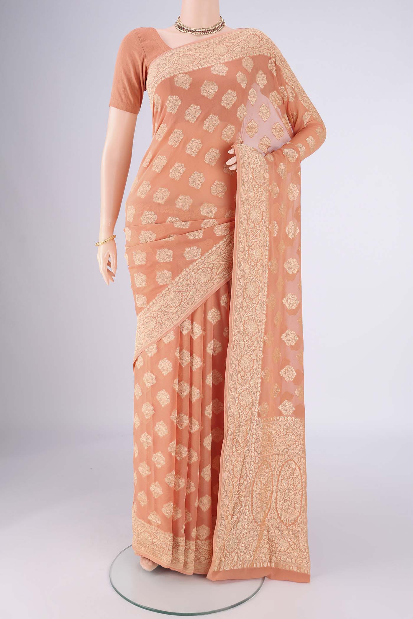 Peach Banarasi Georgette Saree with Zari Butta on the body and Zari Border.  displayed on a mannequin