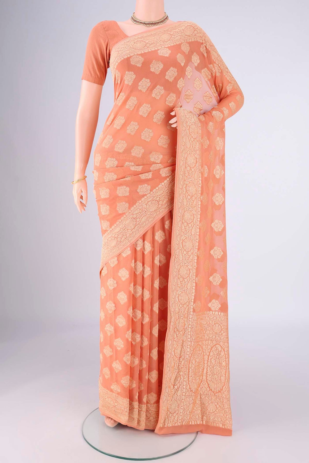 Peach Banarasi Georgette Saree with Zari Butta on the body and Zari Border.  displayed on a mannequin