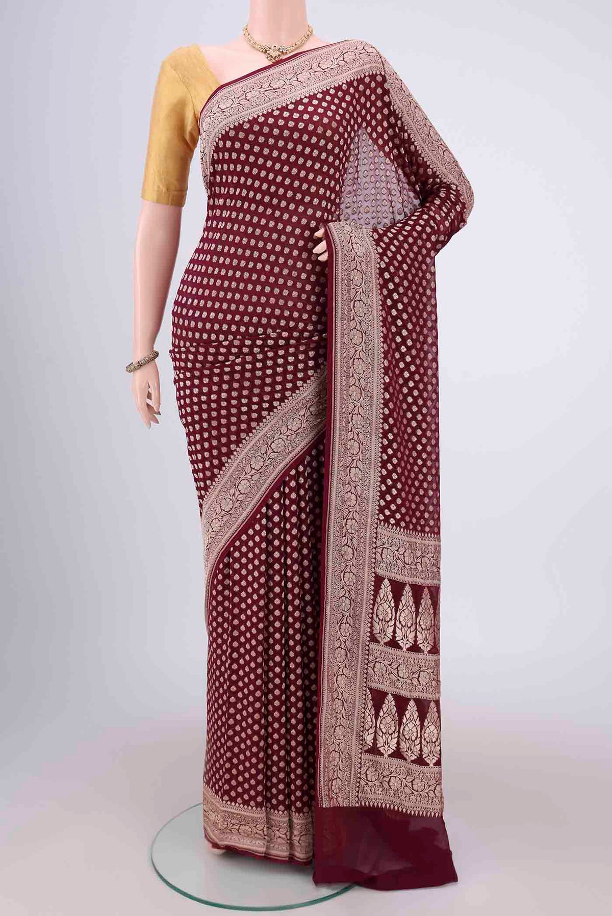 Maroon Banarasi Georgette Saree with Zari Butta on the body and Zari Border.  displayed on a mannequin