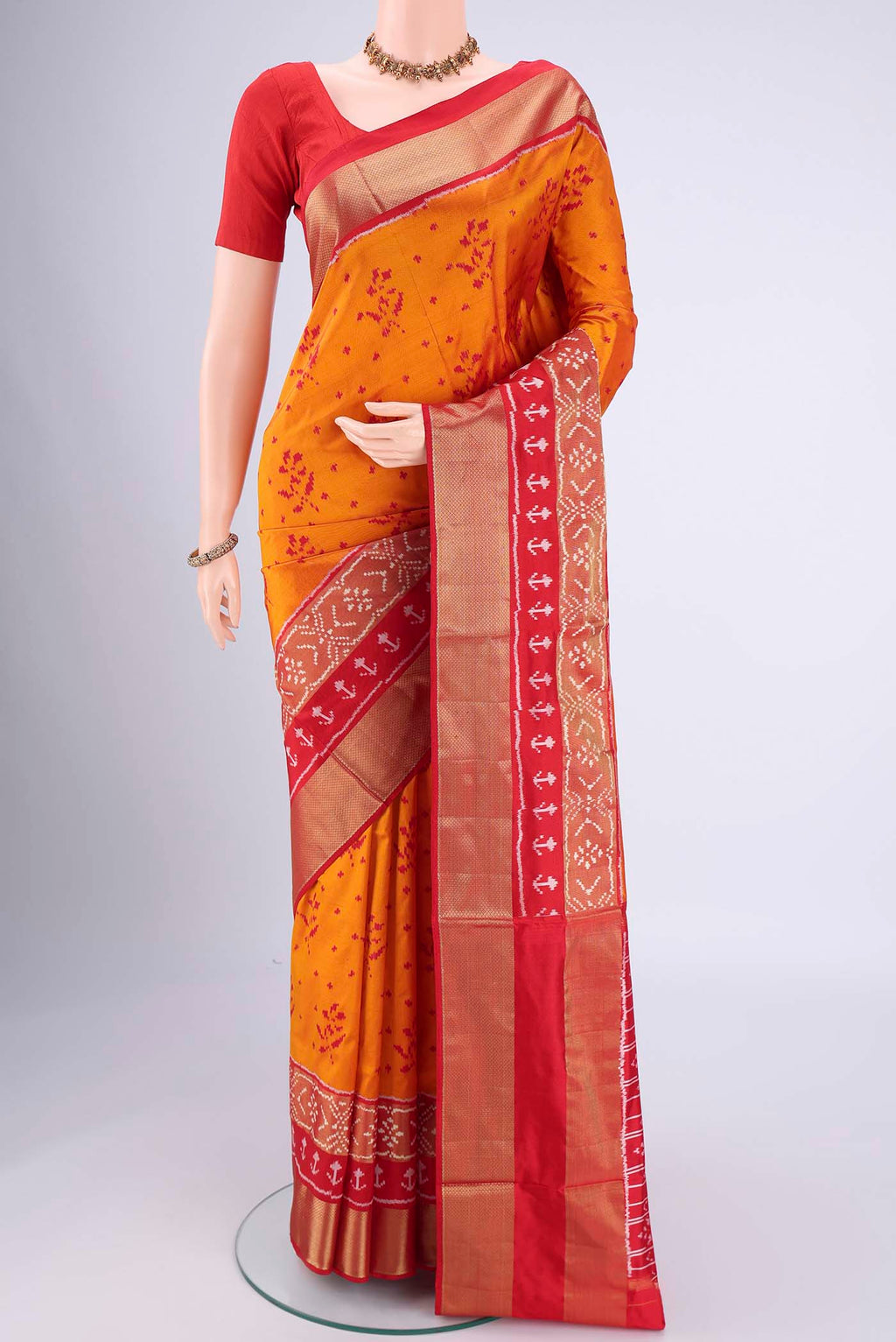 Orange Pochampally Silk Saree with Ikat design on the body and Zari Border.  displayed on a mannequin