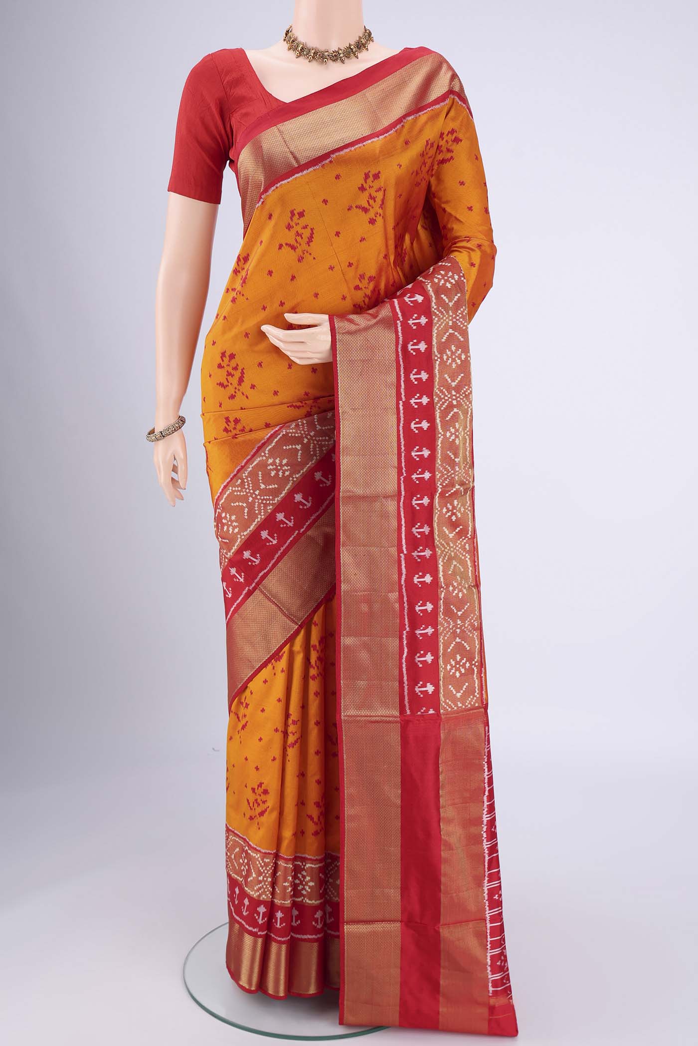 Orange Pochampally Silk Saree with Ikat design on the body and Zari Border.  displayed on a mannequin
