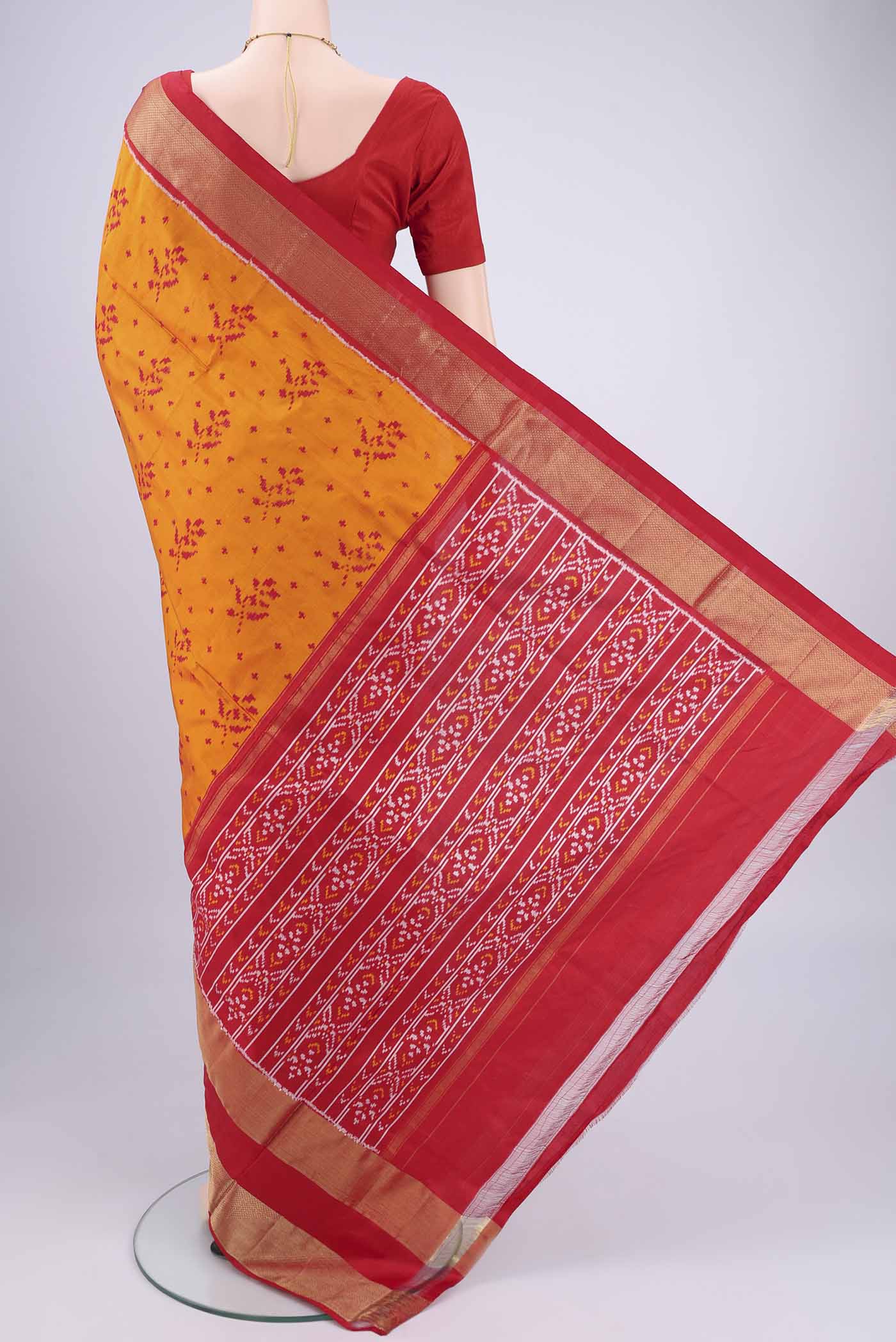 Flat view of Orange Pochampally Silk Saree with Ikat design on the body and Zari Border. 