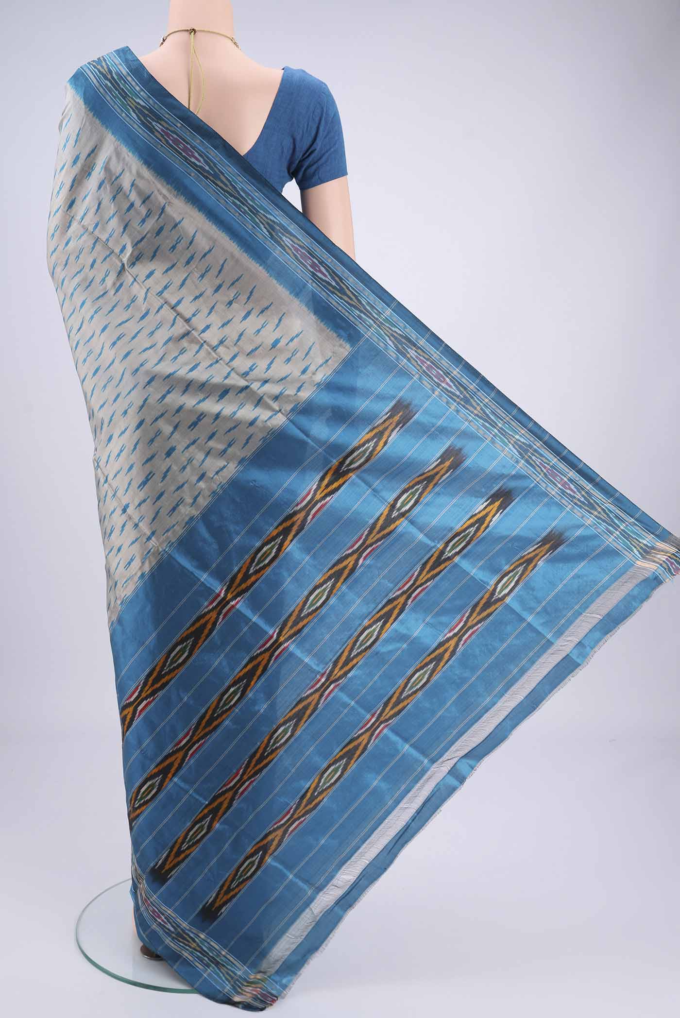Flat view of Grey Pochampally Silk Saree with Ikat design on the body and Zari Border. 