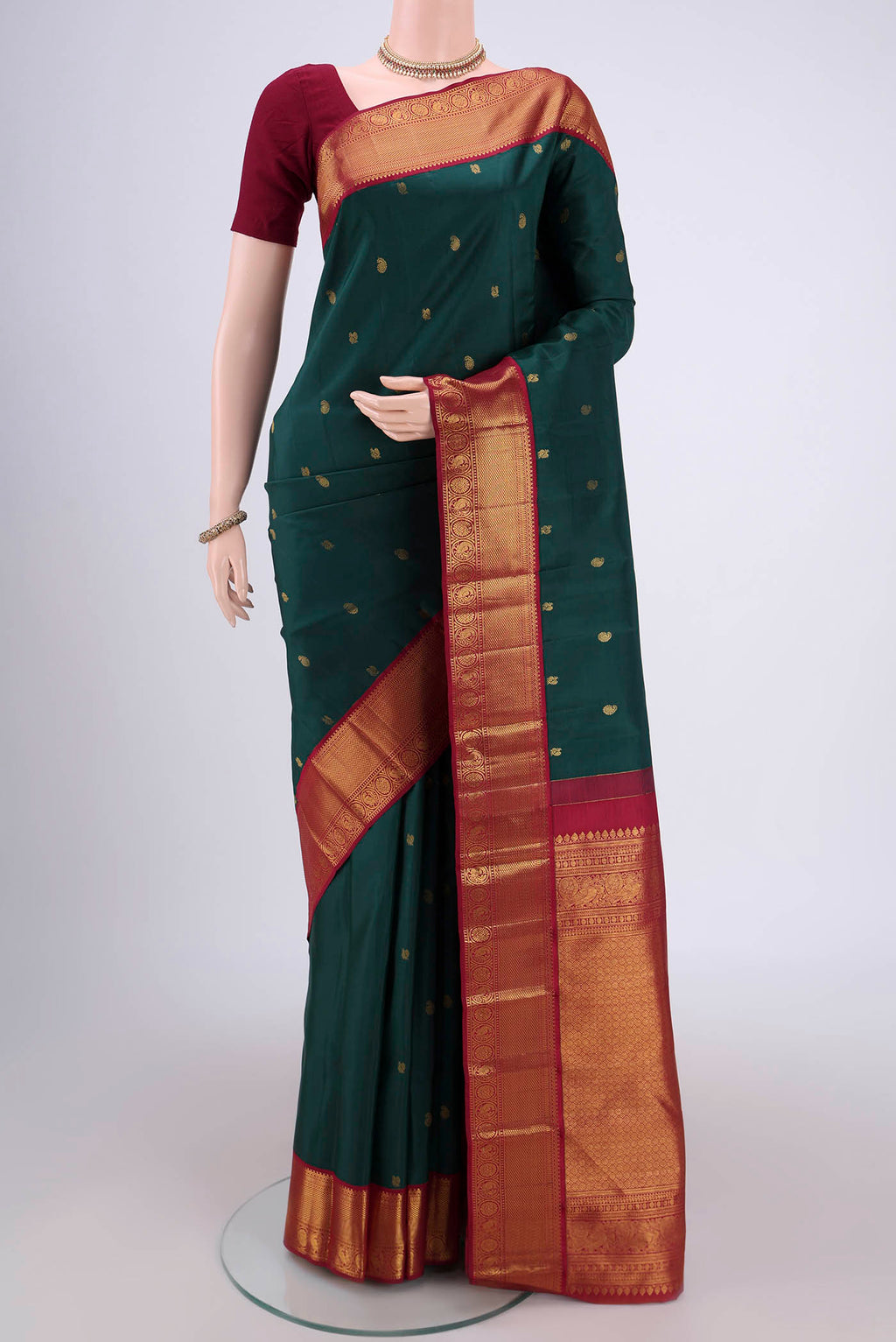 Bottle Green Kanjivaram Silk Saree with Zari Butta on the body and Zari Border.  displayed on a mannequin