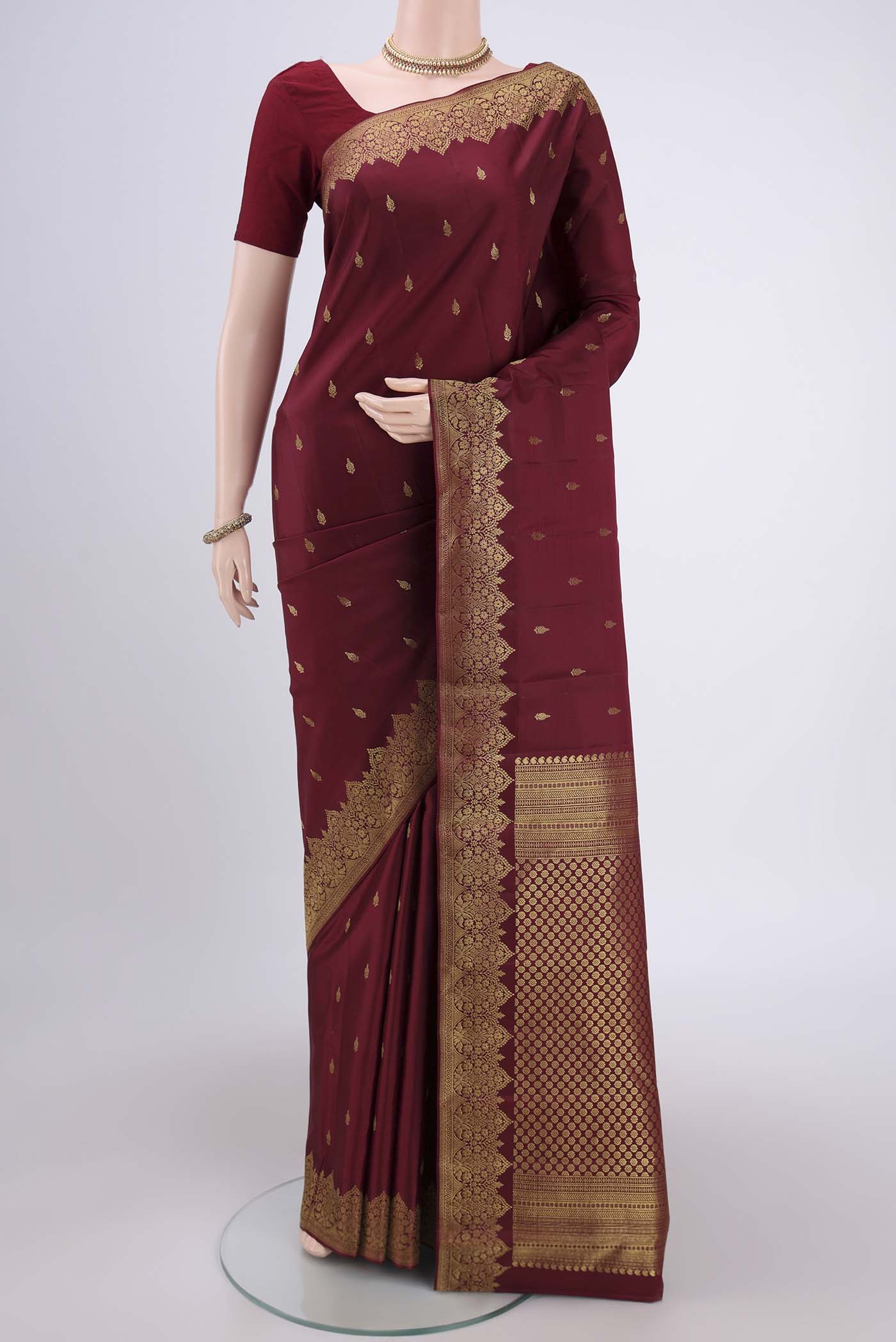 Maroon Kanjivaram Silk Saree with Zari Butta on the body and Zari Border.  displayed on a mannequin