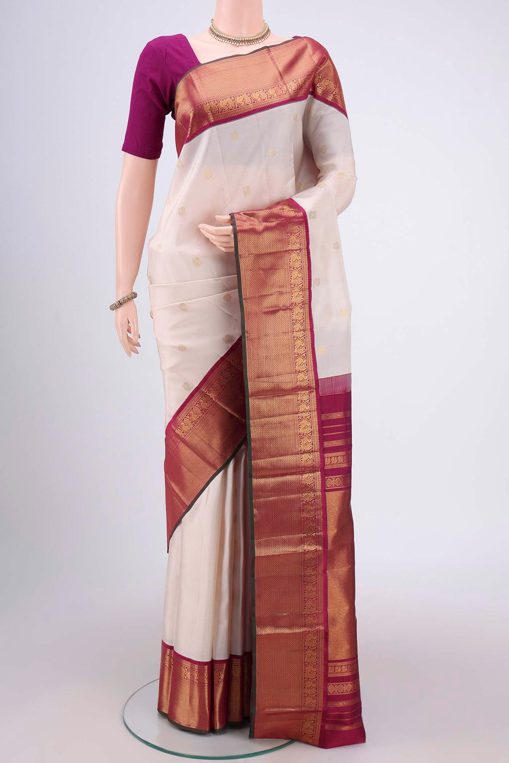 Off White Kanjivaram Silk Saree with Zari Butta on the body and Zari Border.  displayed on a mannequin
