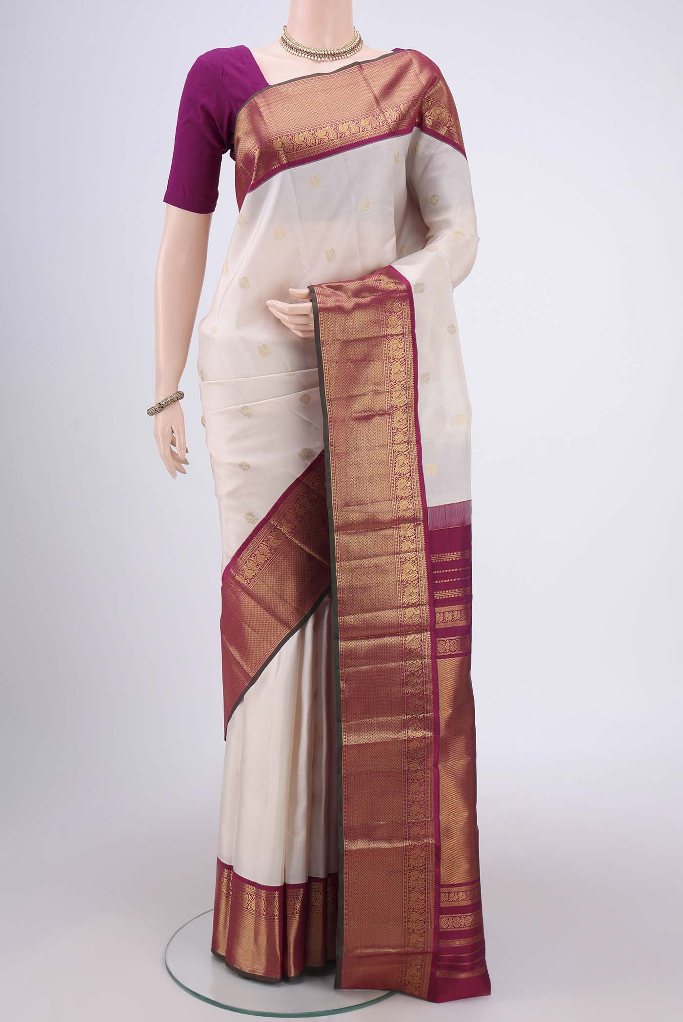 Off White Kanjivaram Silk Saree with Zari Butta on the body and Zari Border.  displayed on a mannequin