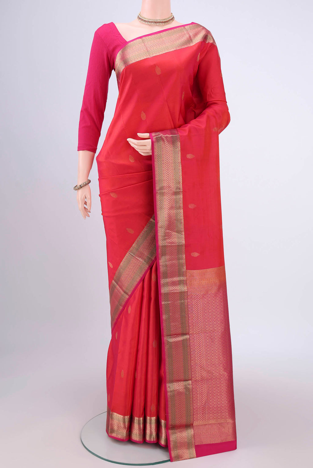 Orange Kanchipuram Silk Saree with Zari Butta on the body and Zari Border.  displayed on a mannequin
