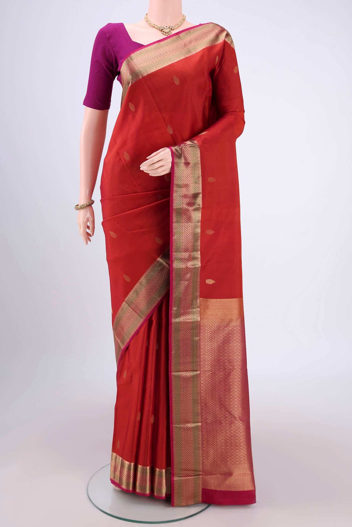 Rust Kanchipuram Silk Saree with Zari Butta on the body and Zari Border.  displayed on a mannequin