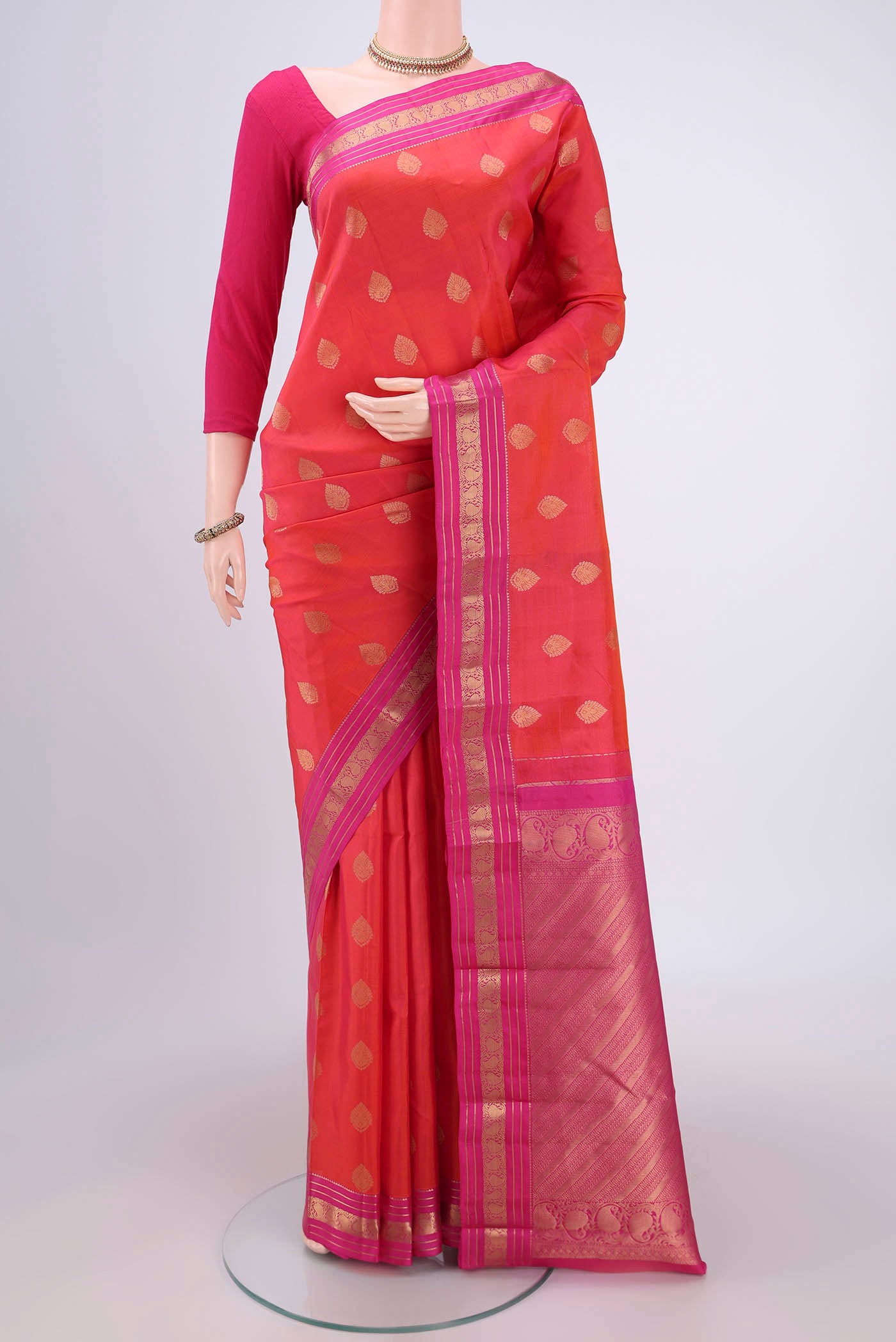 Orange Kanchipuram Silk Saree with Zari Butta on the body and Zari Border.  displayed on a mannequin