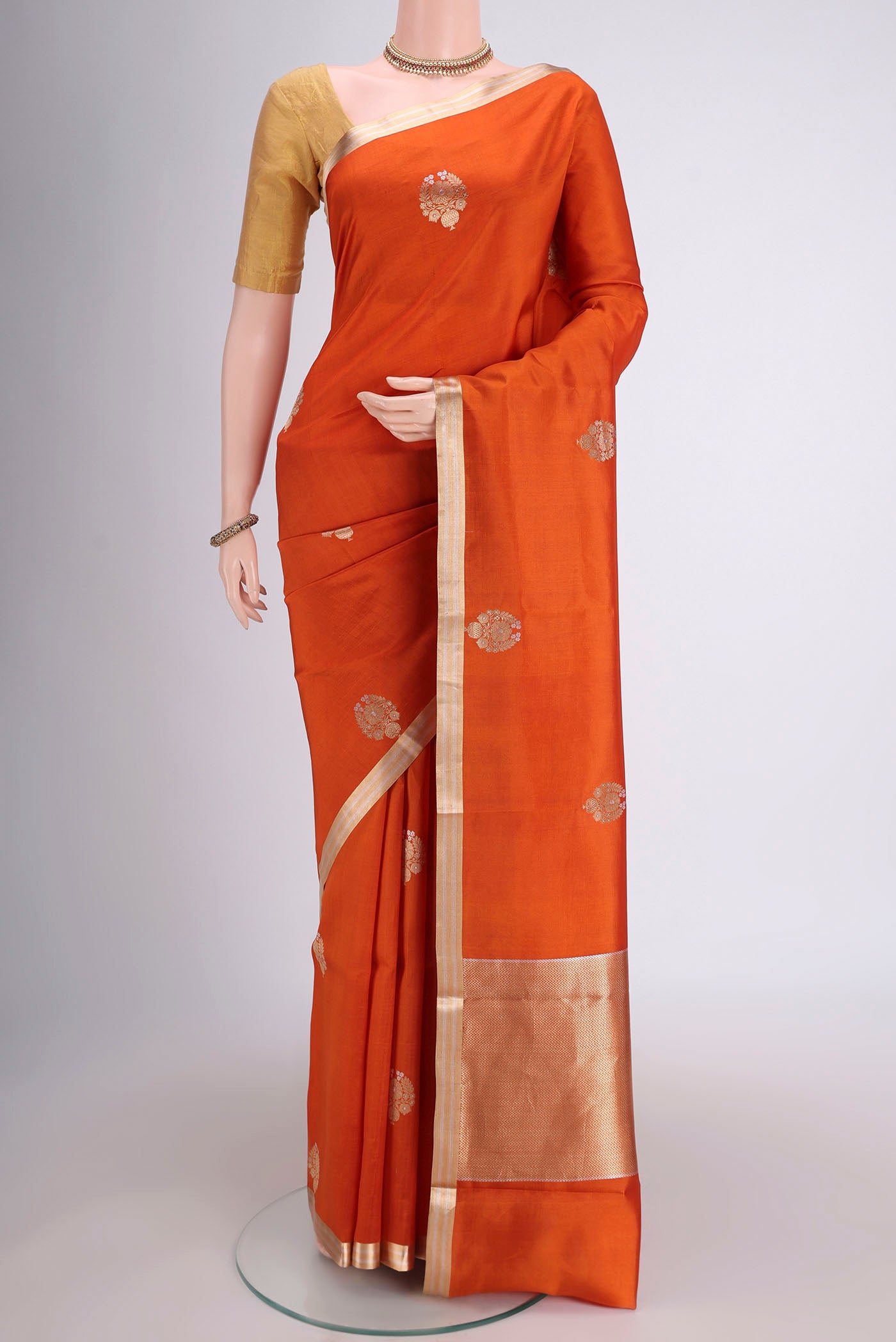 Rust Banarasi Katan Silk Saree with Zari Butta on the body and Zari Border.  displayed on a mannequin