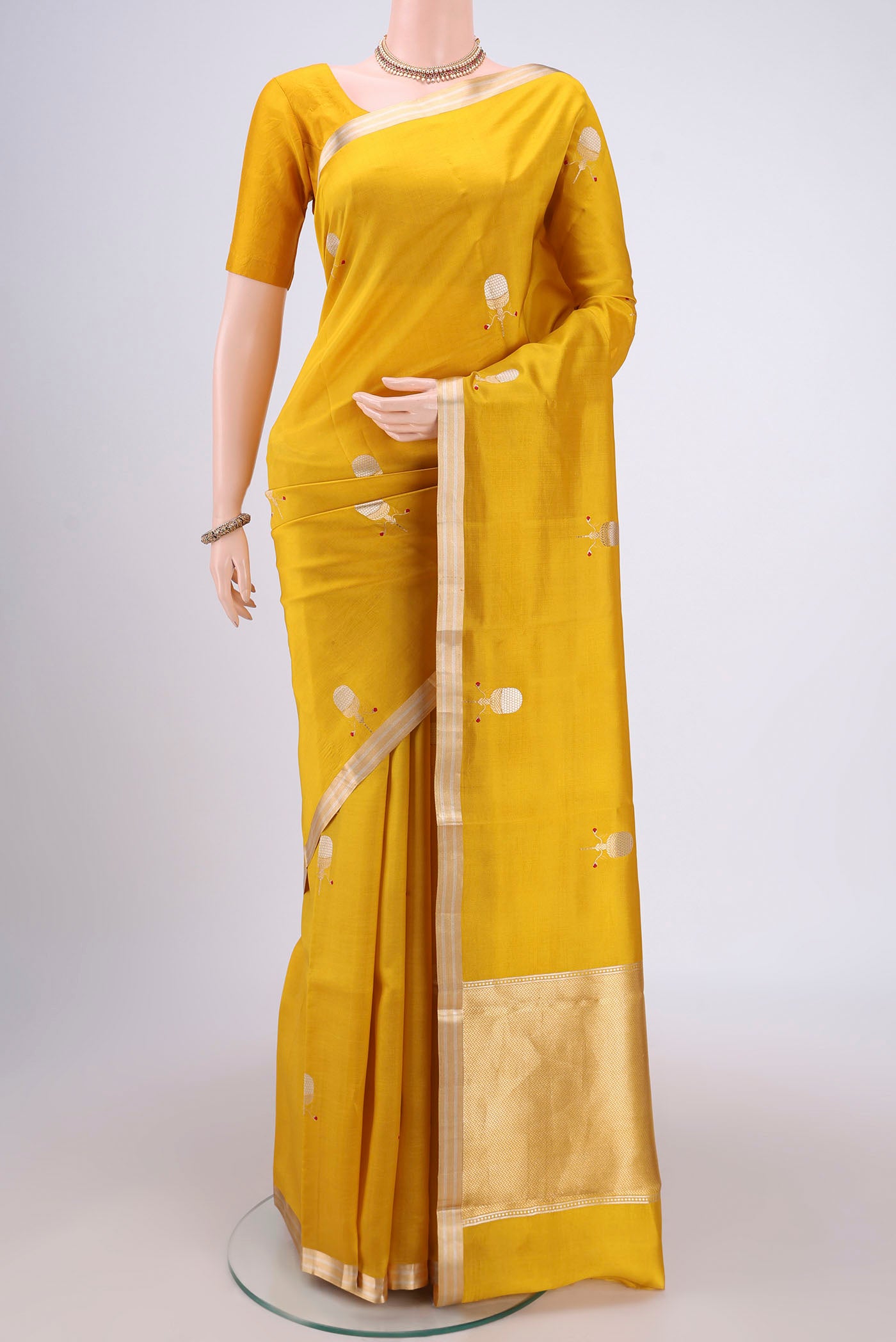 Mustard Banarasi Katan Silk Saree with Zari Butta on the body and Zari Border.  displayed on a mannequin
