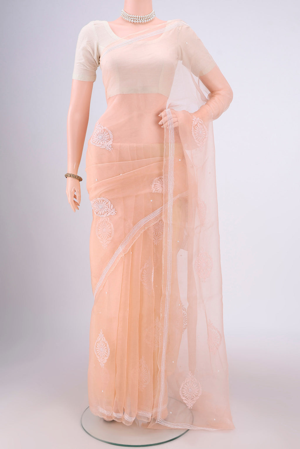 Peach Organza Silk Saree with Embroidery on the body and Zari Border.  displayed on a mannequin