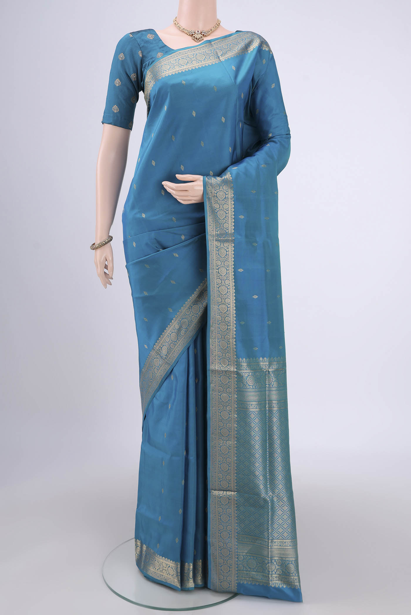 Turquoise Soft Silk Saree with Zari Butta on the body and Zari Border.  displayed on a mannequin