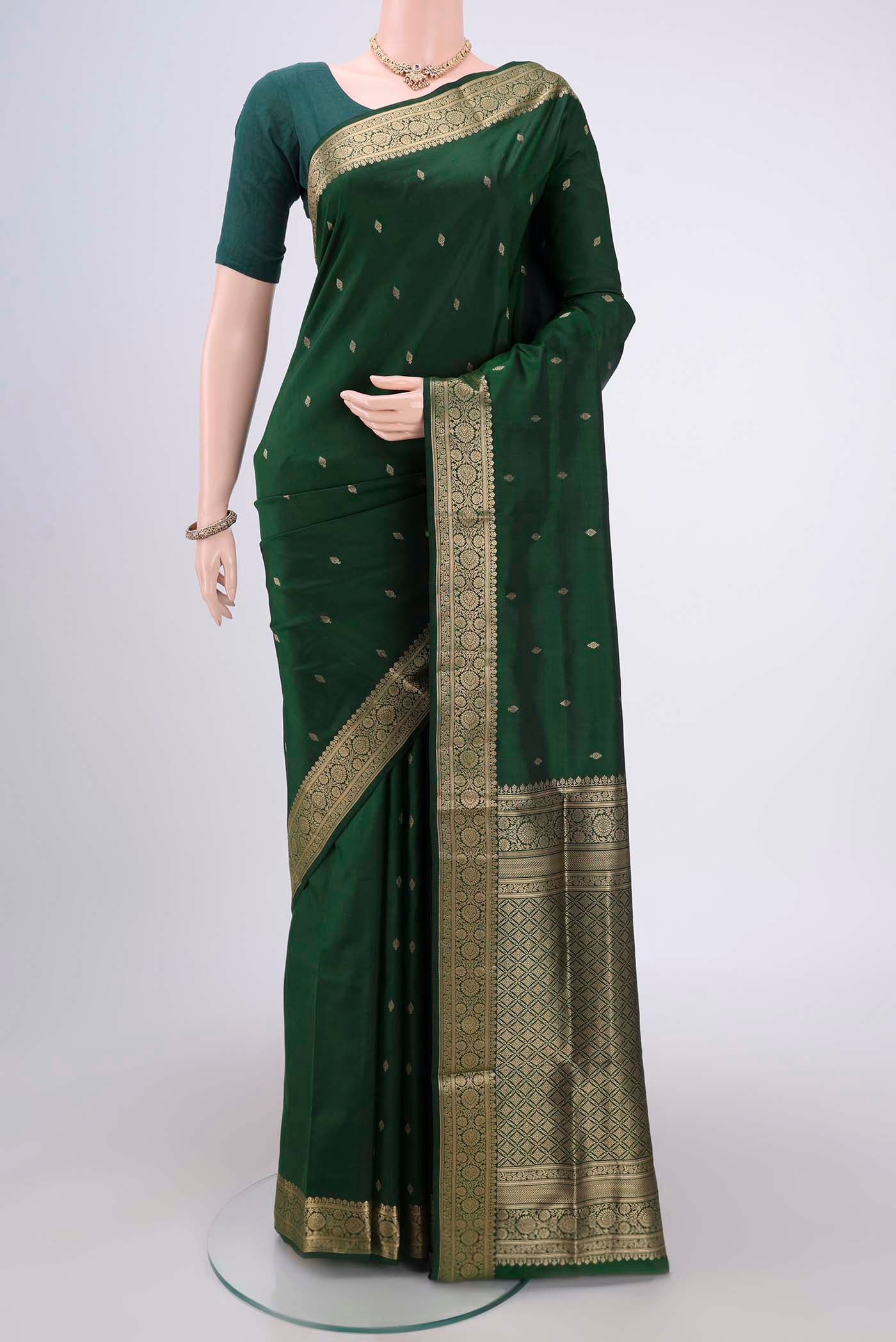 Bottle Green Soft Silk Saree with Zari Butta on the body and Zari Border.  displayed on a mannequin