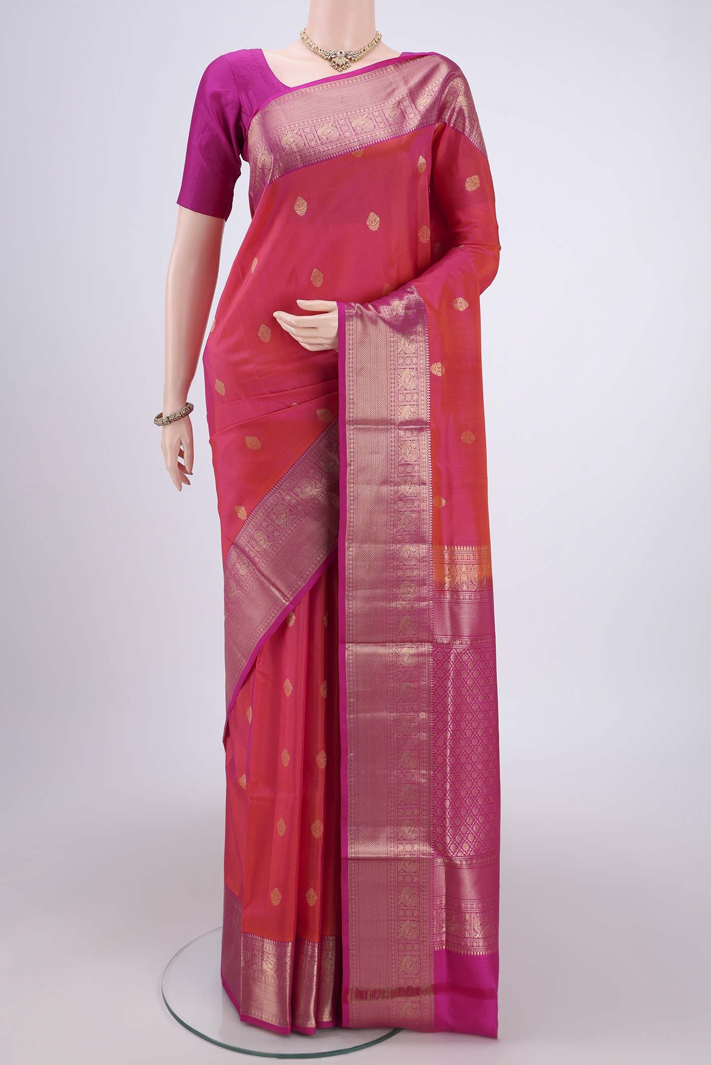 Orange Soft Silk Saree with Zari Butta on the body and Zari Border.  displayed on a mannequin