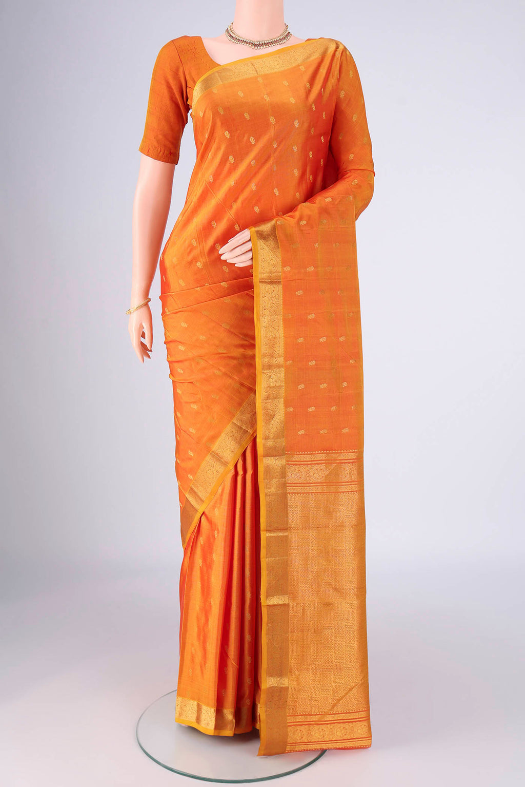Brick Orange Kanchipuram Silk Saree with Zari Butta on the body and Zari Border.  displayed on a mannequin