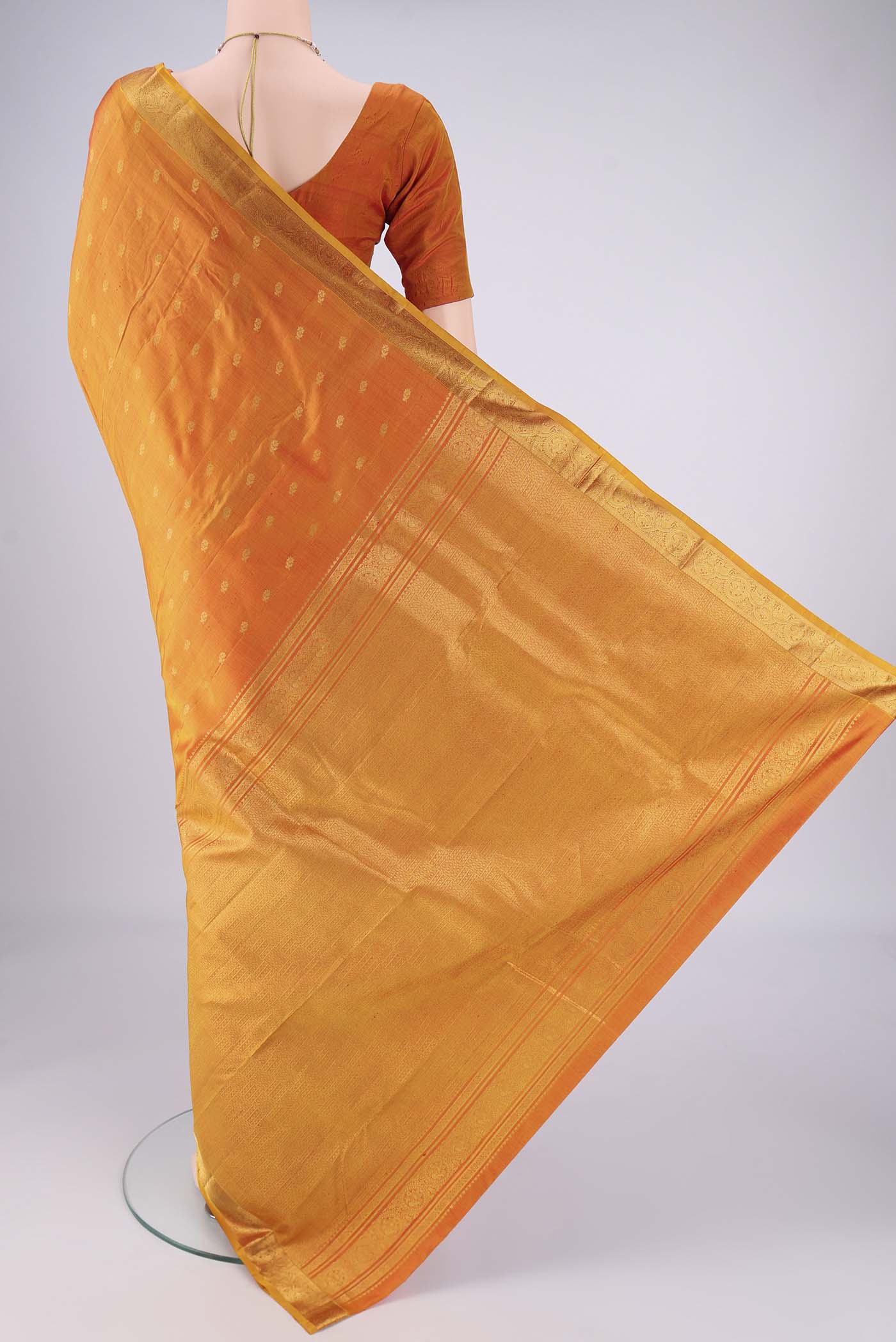 Flat view of Brick Orange Kanchipuram Silk Saree with Zari Butta on the body and Zari Border. 
