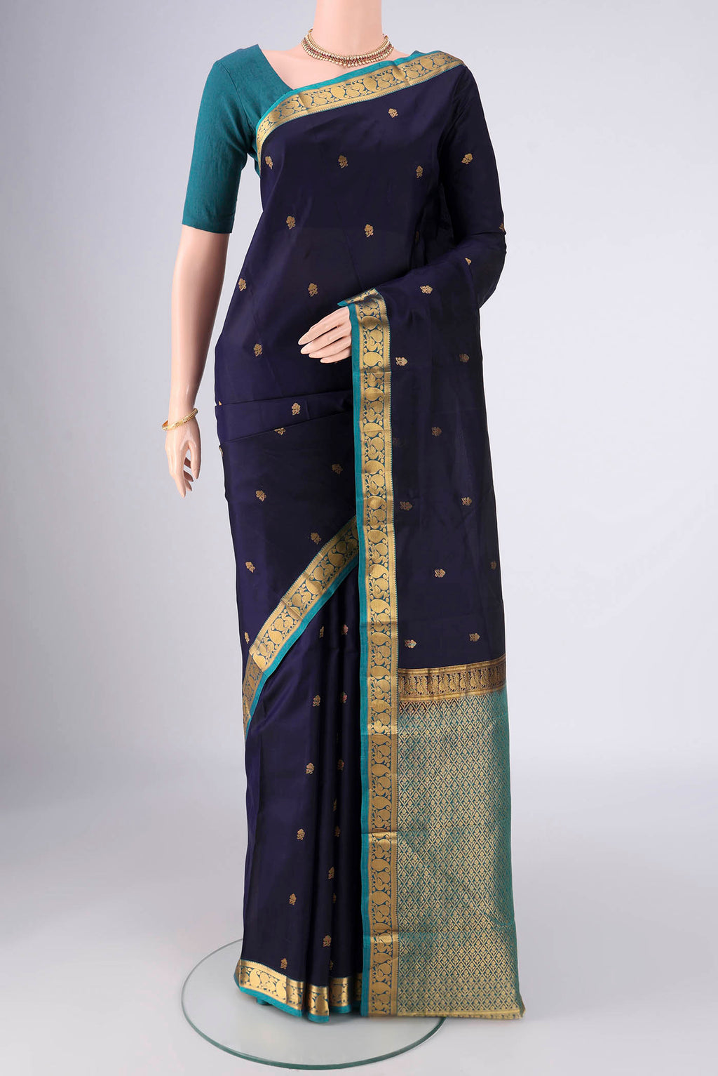 Navy Blue Kanjivaram Silk Saree with Zari Butta on the body and Zari Border.  displayed on a mannequin