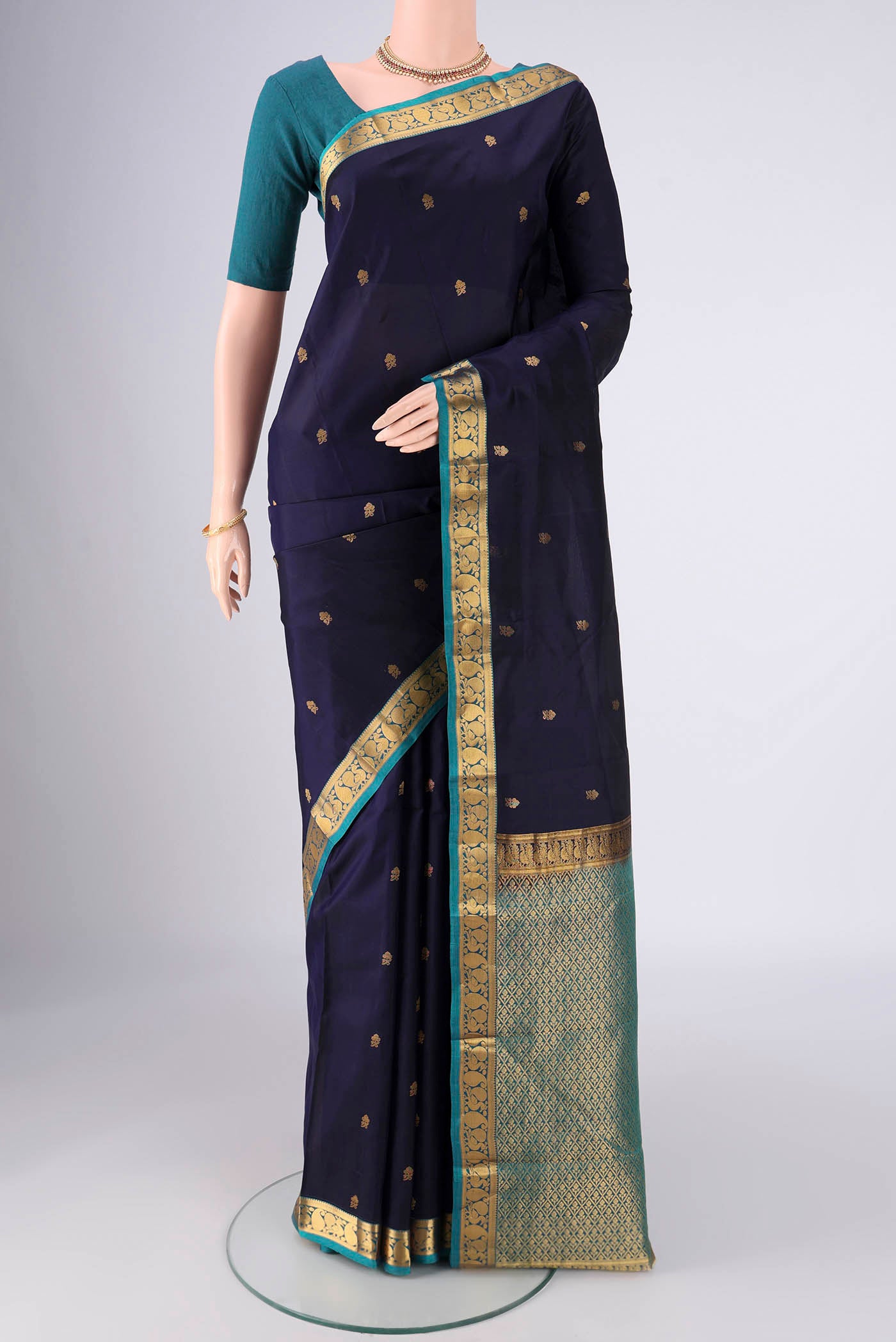 Navy Blue Kanjivaram Silk Saree with Zari Butta on the body and Zari Border.  displayed on a mannequin