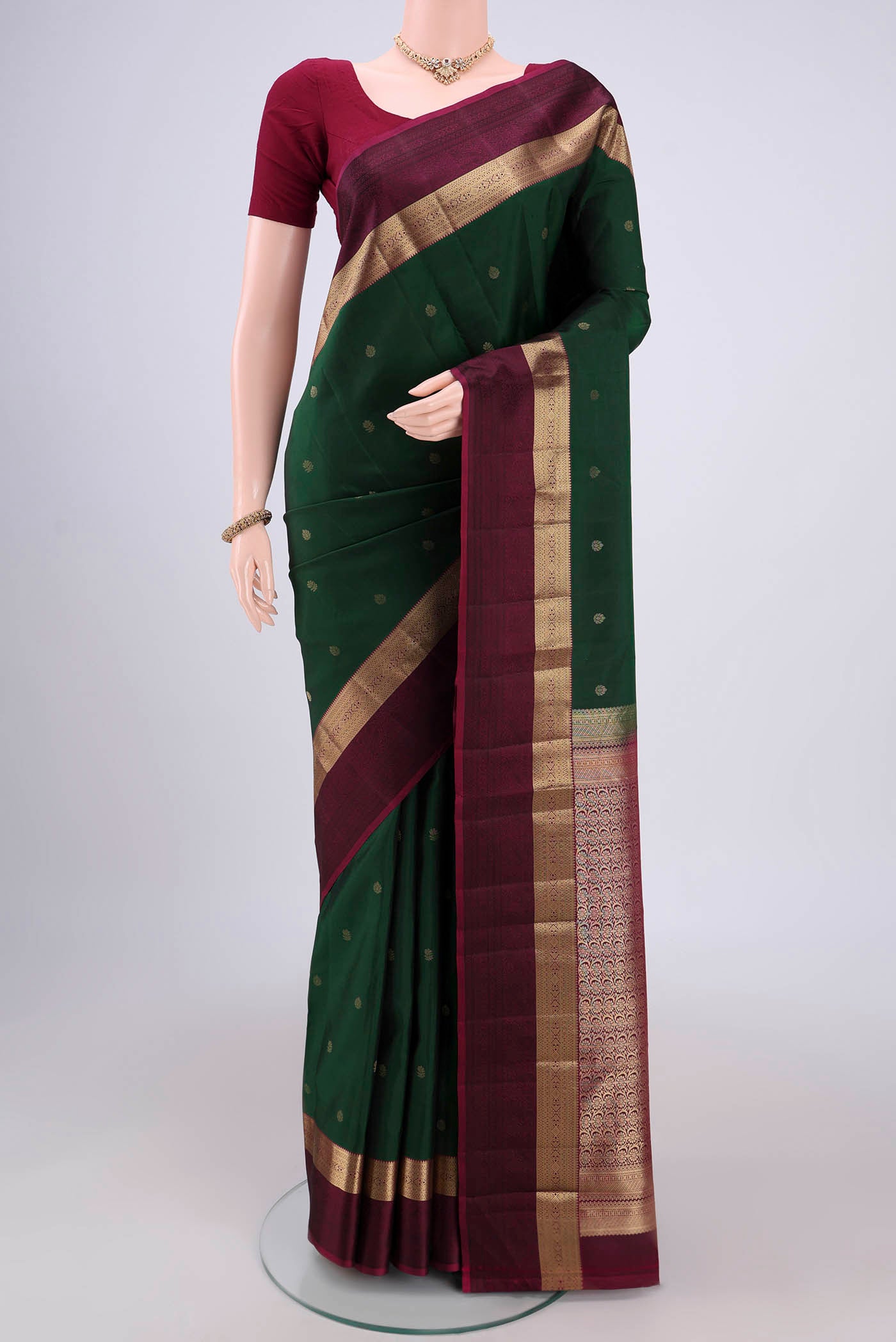 Bottle Green Kanchipuram Silk Saree with Zari Butta on the body and Zari And Thread Border.  displayed on a mannequin