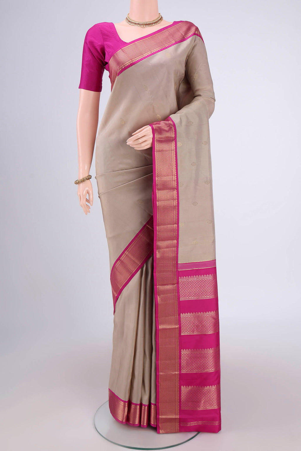 Beige Kanchipuram Silk Saree with Zari Butta on the body and Zari Border.  displayed on a mannequin