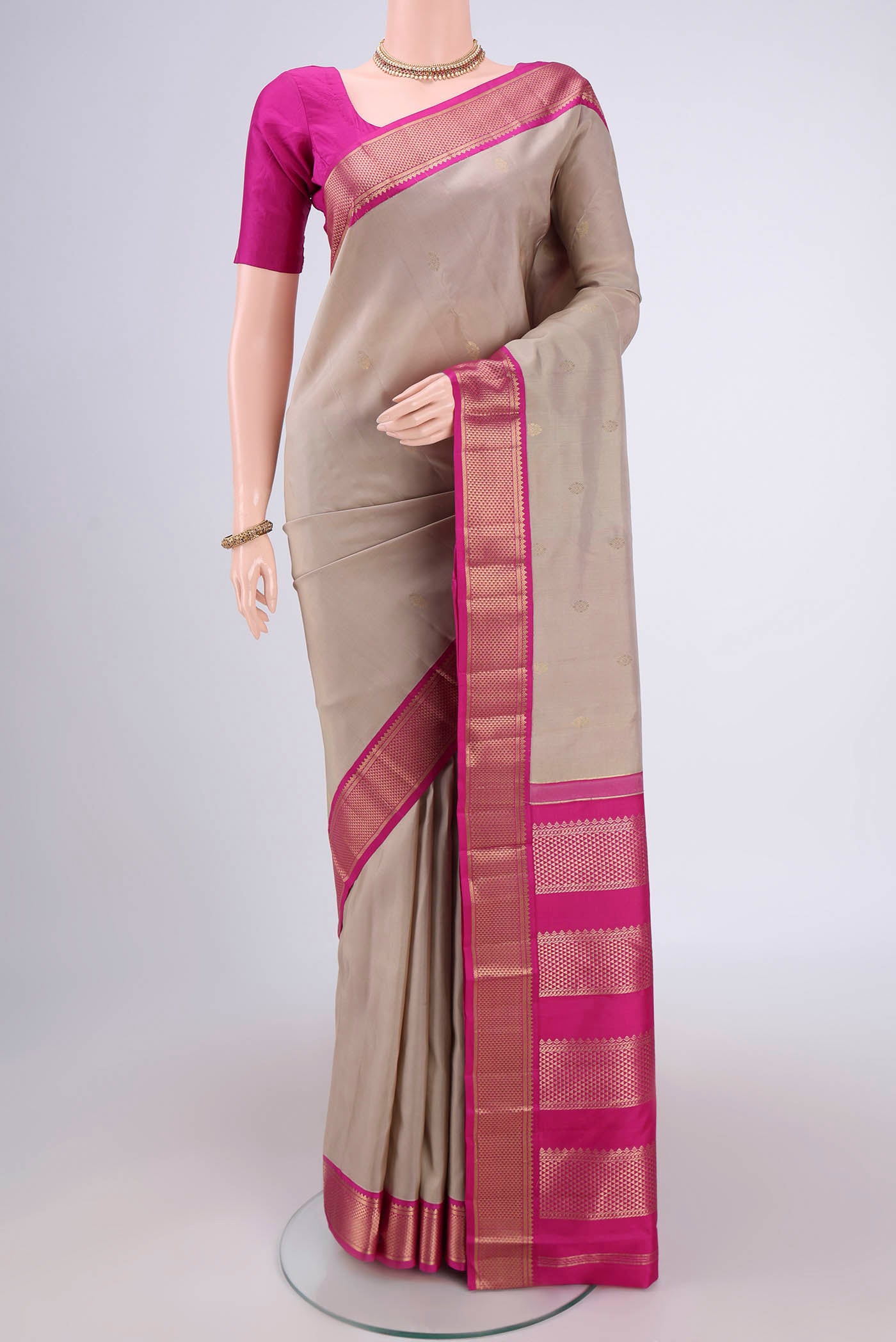 Beige Kanchipuram Silk Saree with Zari Butta on the body and Zari Border.  displayed on a mannequin