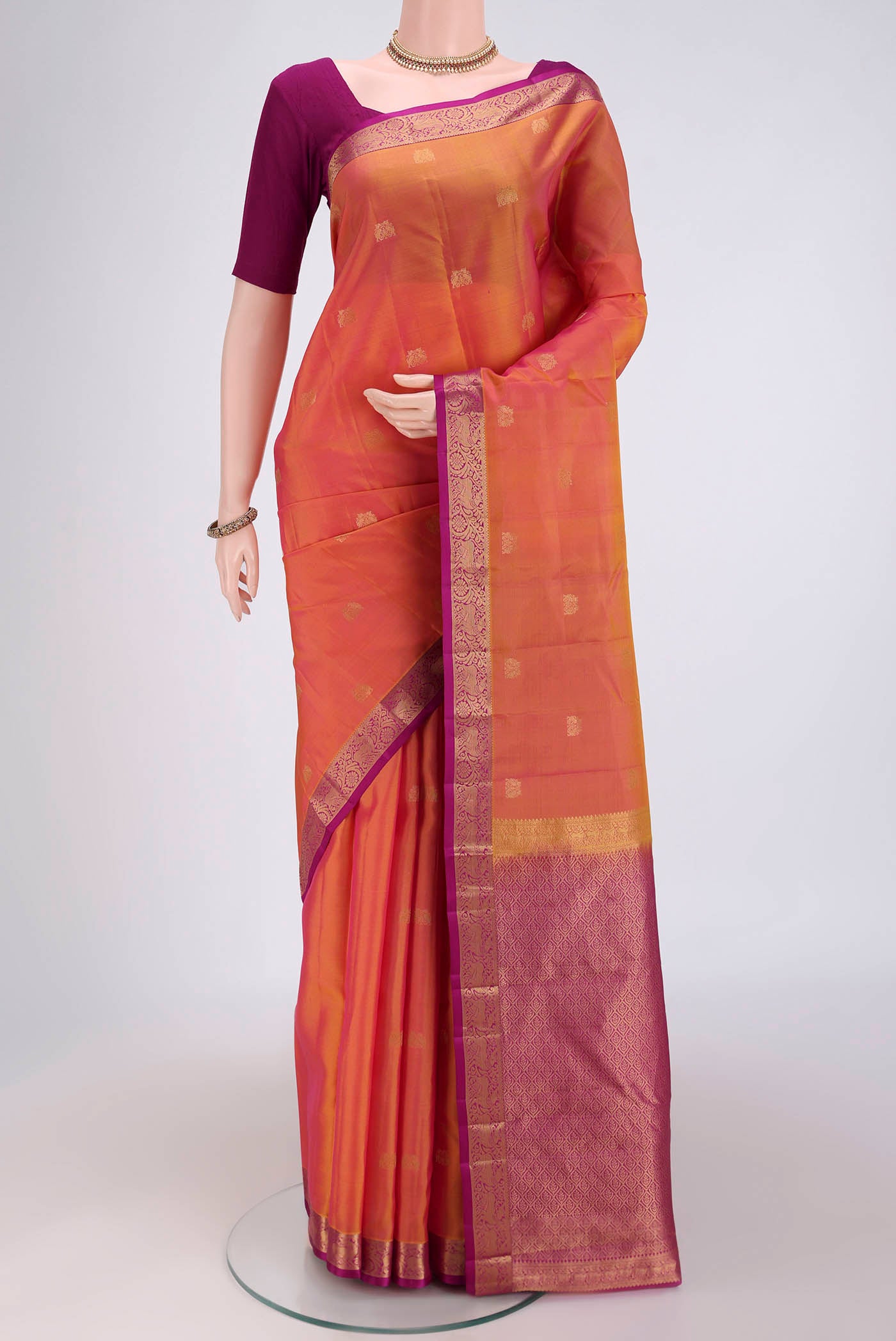 Brick Orange Kanjivaram Silk Saree with Zari Butta on the body and Zari Border.  displayed on a mannequin
