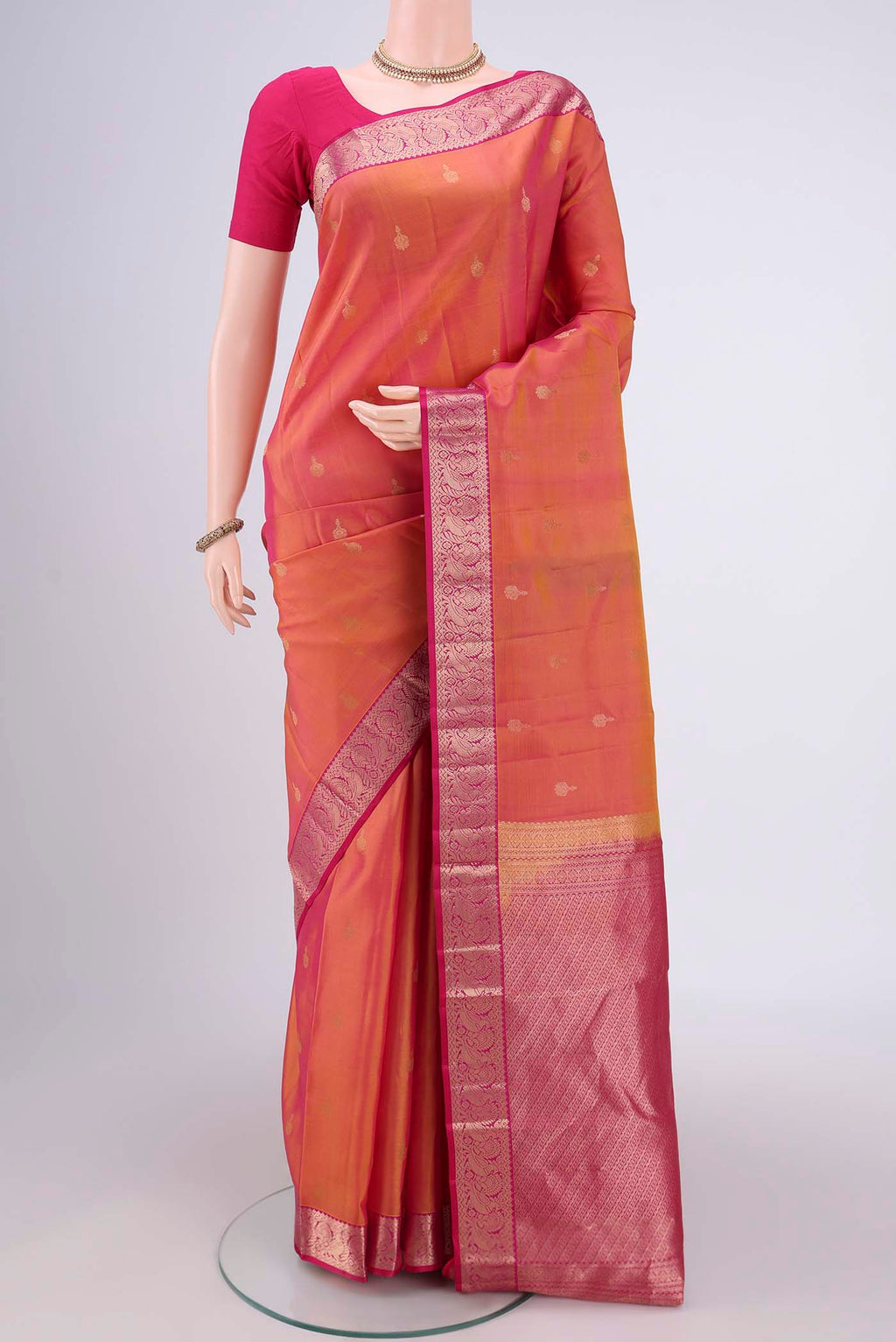Brick Orange Kanjivaram Silk Saree with Zari Butta on the body and Zari Border.  displayed on a mannequin