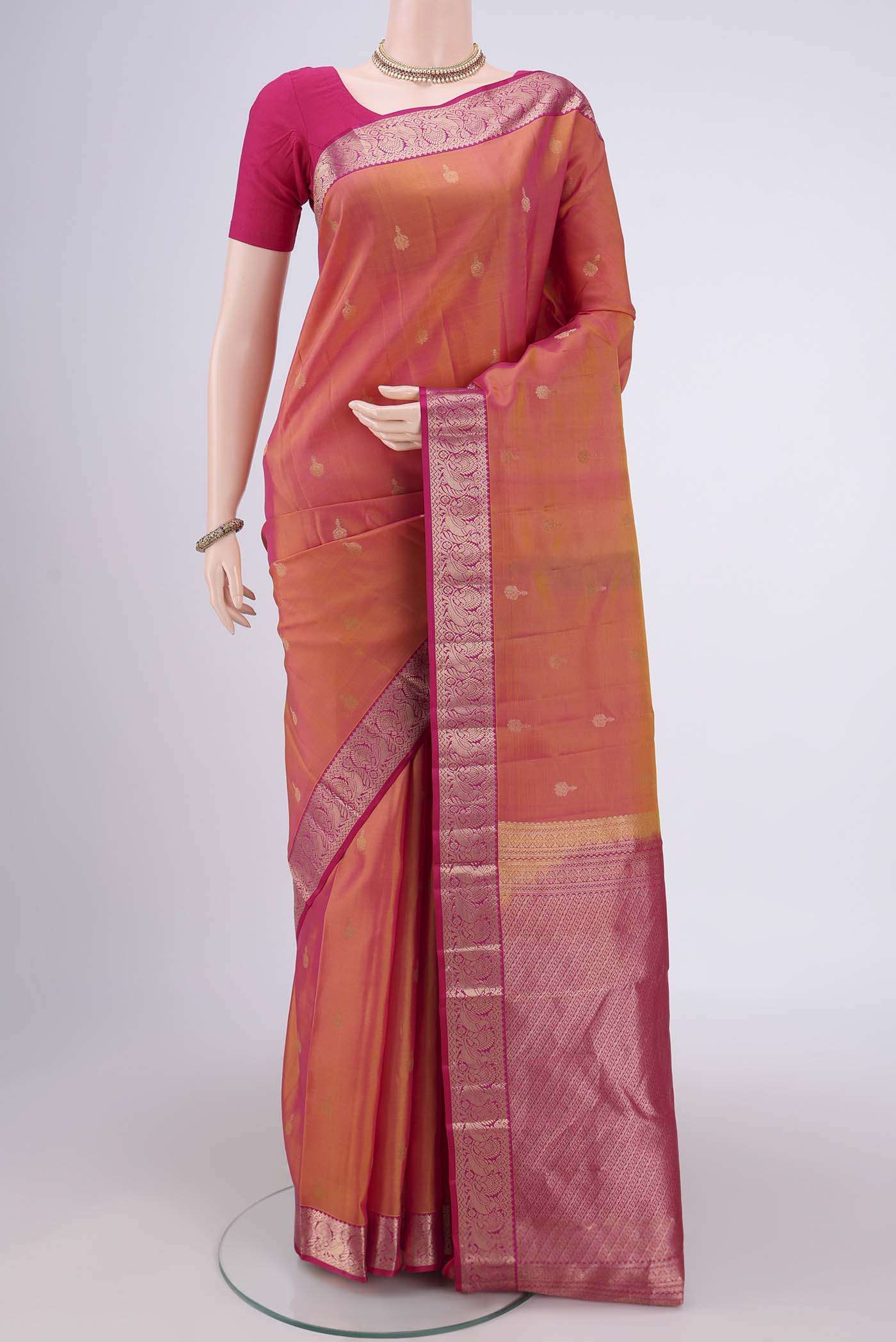 Brick Orange Kanjivaram Silk Saree with Zari Butta on the body and Zari Border.  displayed on a mannequin