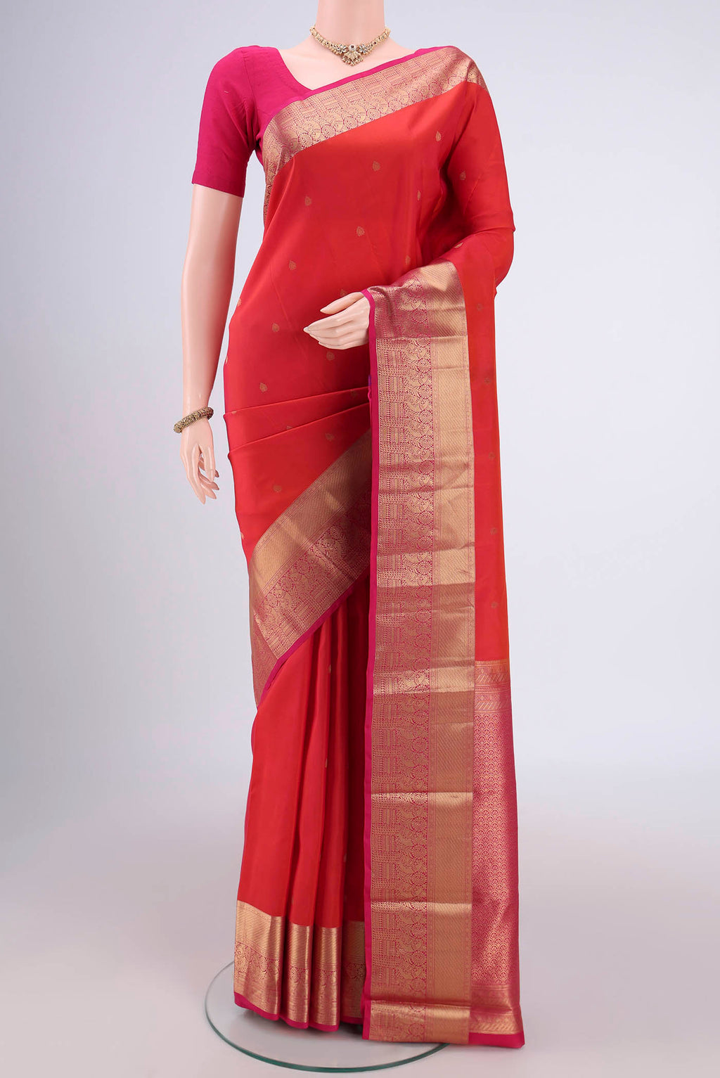 Orange Kanchipuram Silk Saree with Zari Butta on the body and Zari Border.  displayed on a mannequin