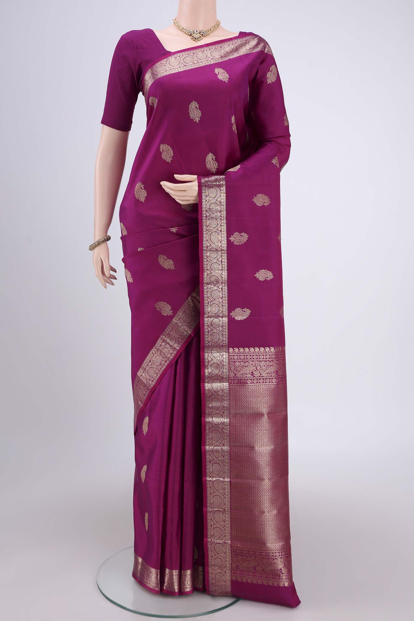 Magenta Kanjivaram Silk Saree with Zari Butta on the body and Zari Border.  displayed on a mannequin