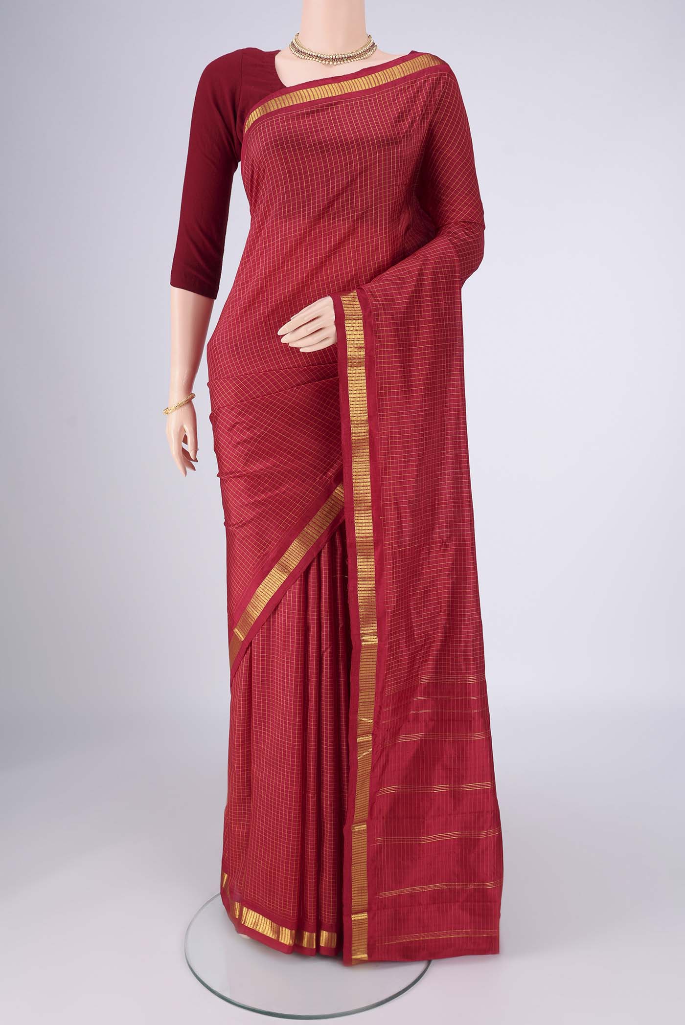 Maroon Kanchipuram Silk Saree with Checked design on the body and Zari Border.  displayed on a mannequin