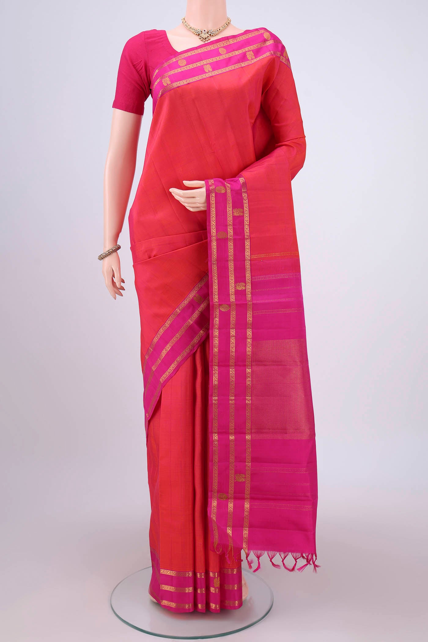 Orange Dual Tone Kanchipuram Silk Saree with Plain Body and Attached Border.  displayed on a mannequin