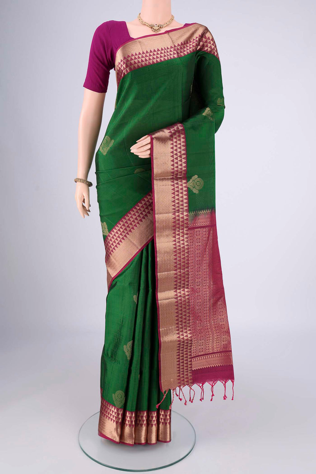 Bottle Green Soft Silk Saree with Zari Butta on the body and Zari Border.  displayed on a mannequin