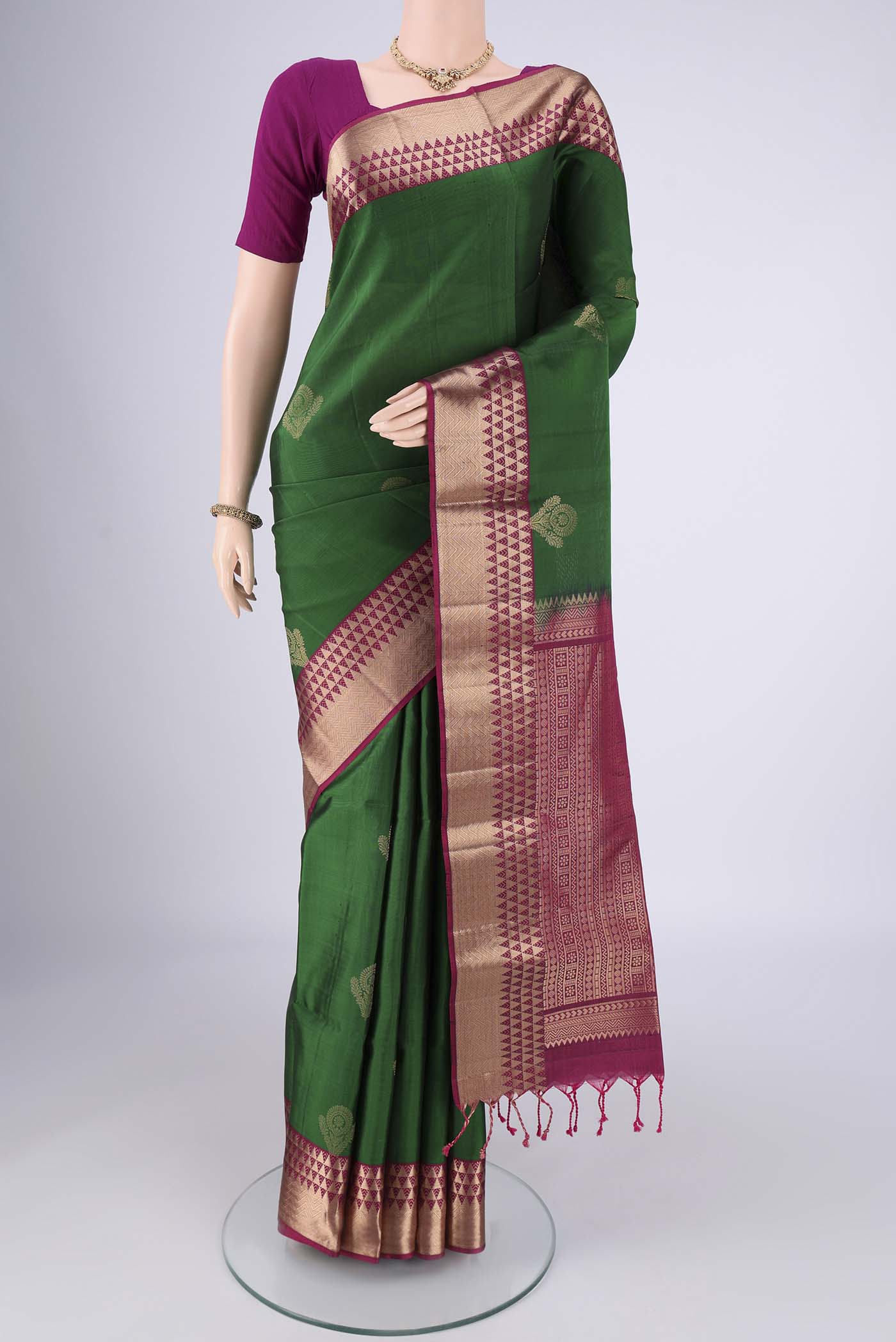 Bottle Green Soft Silk Saree with Zari Butta on the body and Zari Border.  displayed on a mannequin