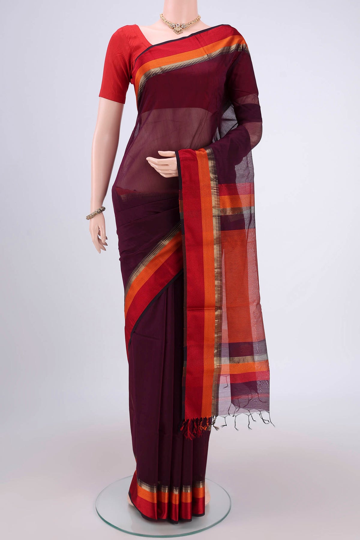 Burgundy Maheshwari Silk Cotton Saree with Plain Body and Zari Border.  displayed on a mannequin