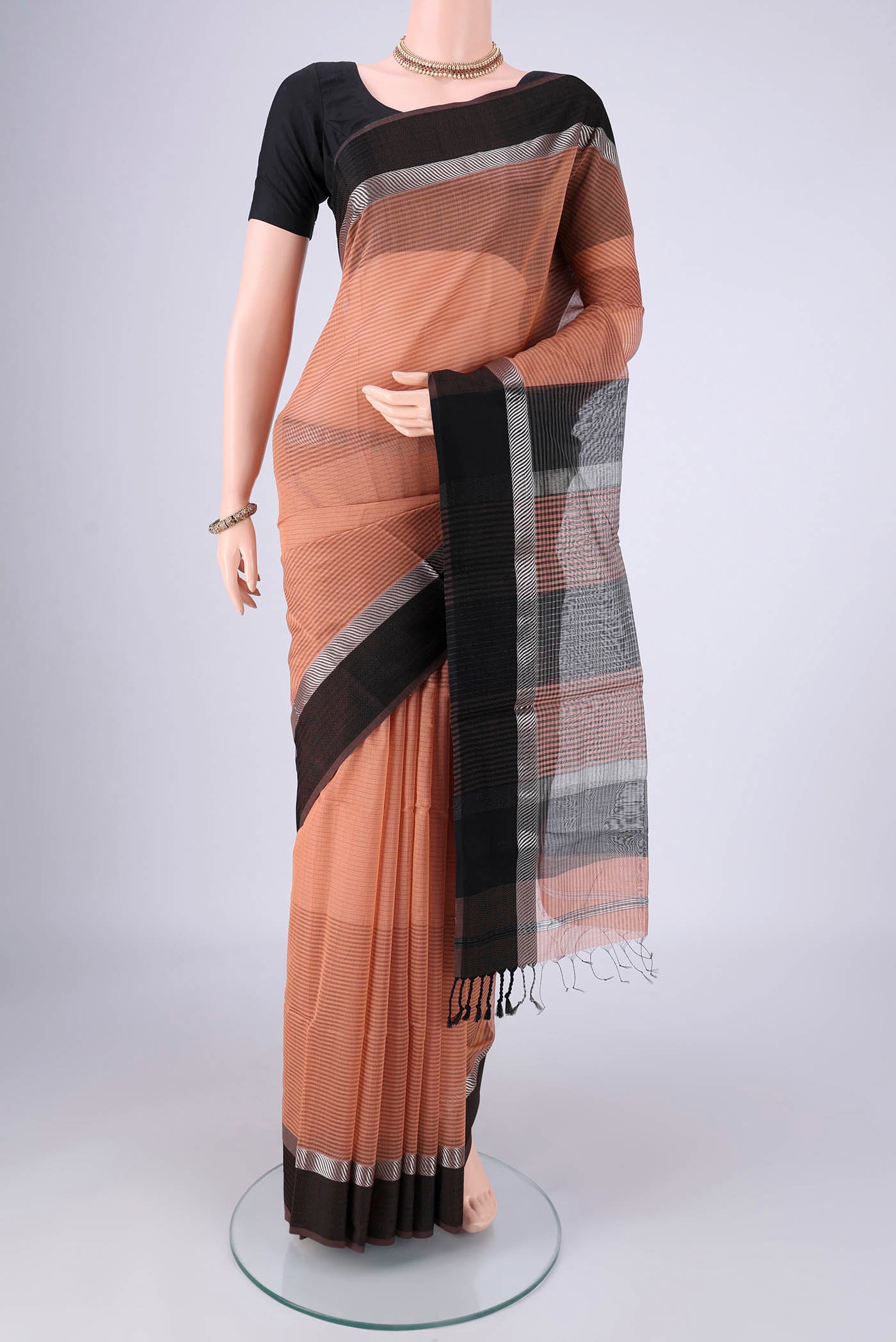 Peach Maheshwari Silk Cotton Saree with Stripes on the body and Thread Border.  displayed on a mannequin