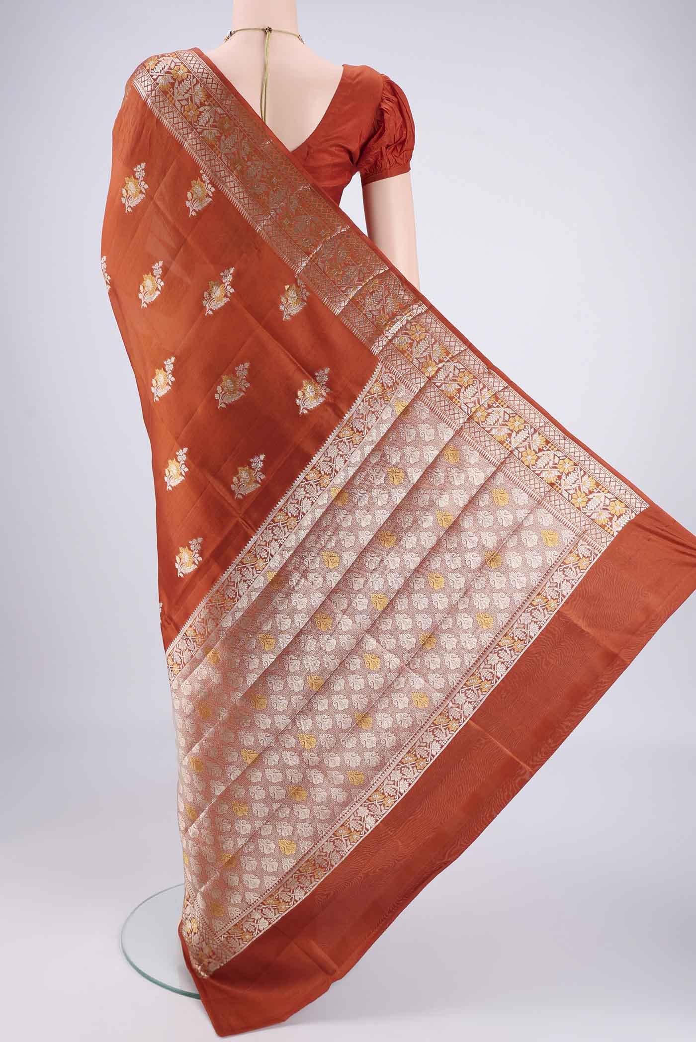 Flat view of Rust Banarasi Raw Silk Saree with Zari Butta on the body and Zari Border. 