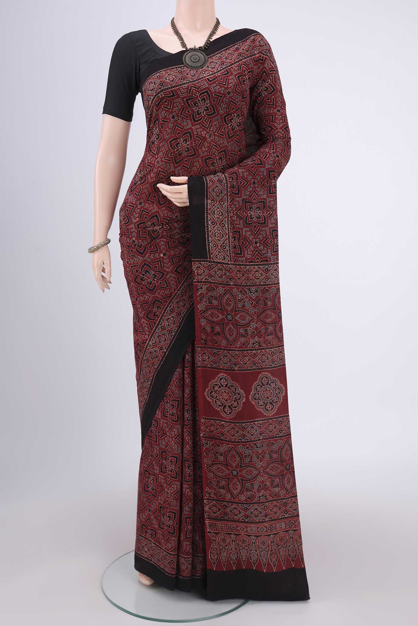 Maroon Maheshwari Silk Cotton Saree with Ajrakh Print on the body and Plain Border.  displayed on a mannequin