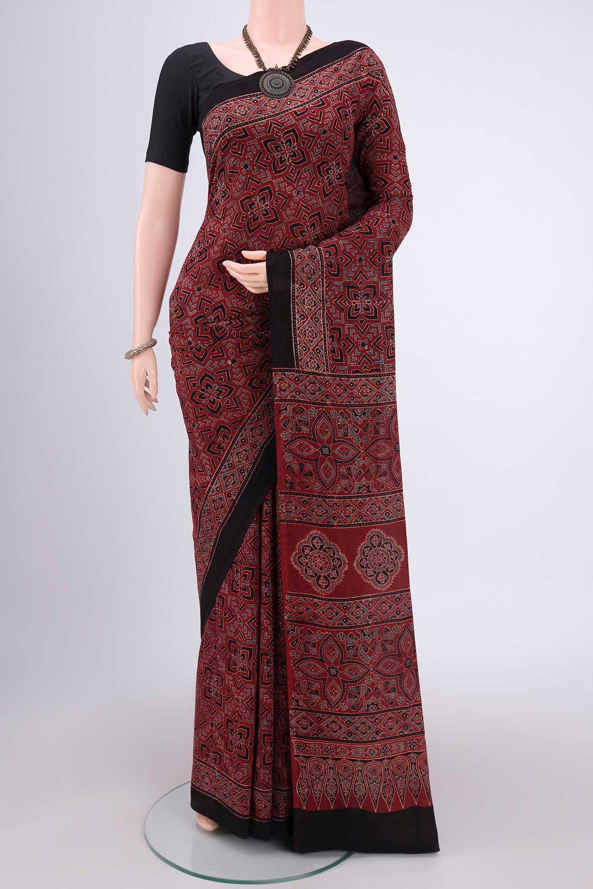 Maroon Maheshwari Silk Cotton Saree with Ajrakh Print on the body and Plain Border.  displayed on a mannequin