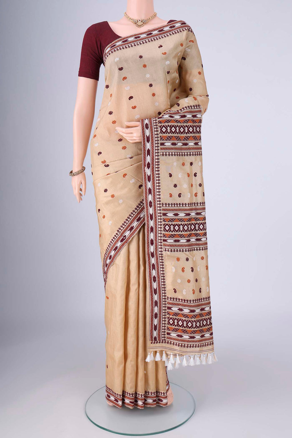 Beige Assam Silk Saree with Thread Butta on the body and Thread Border.  displayed on a mannequin