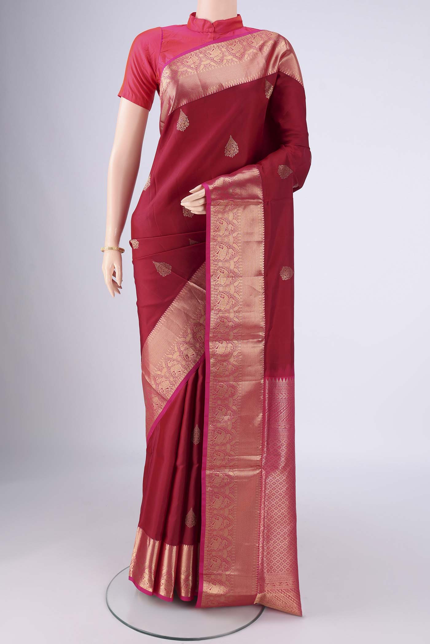 Maroon Soft Silk Saree with Zari Butta on the body and Zari Border.  displayed on a mannequin