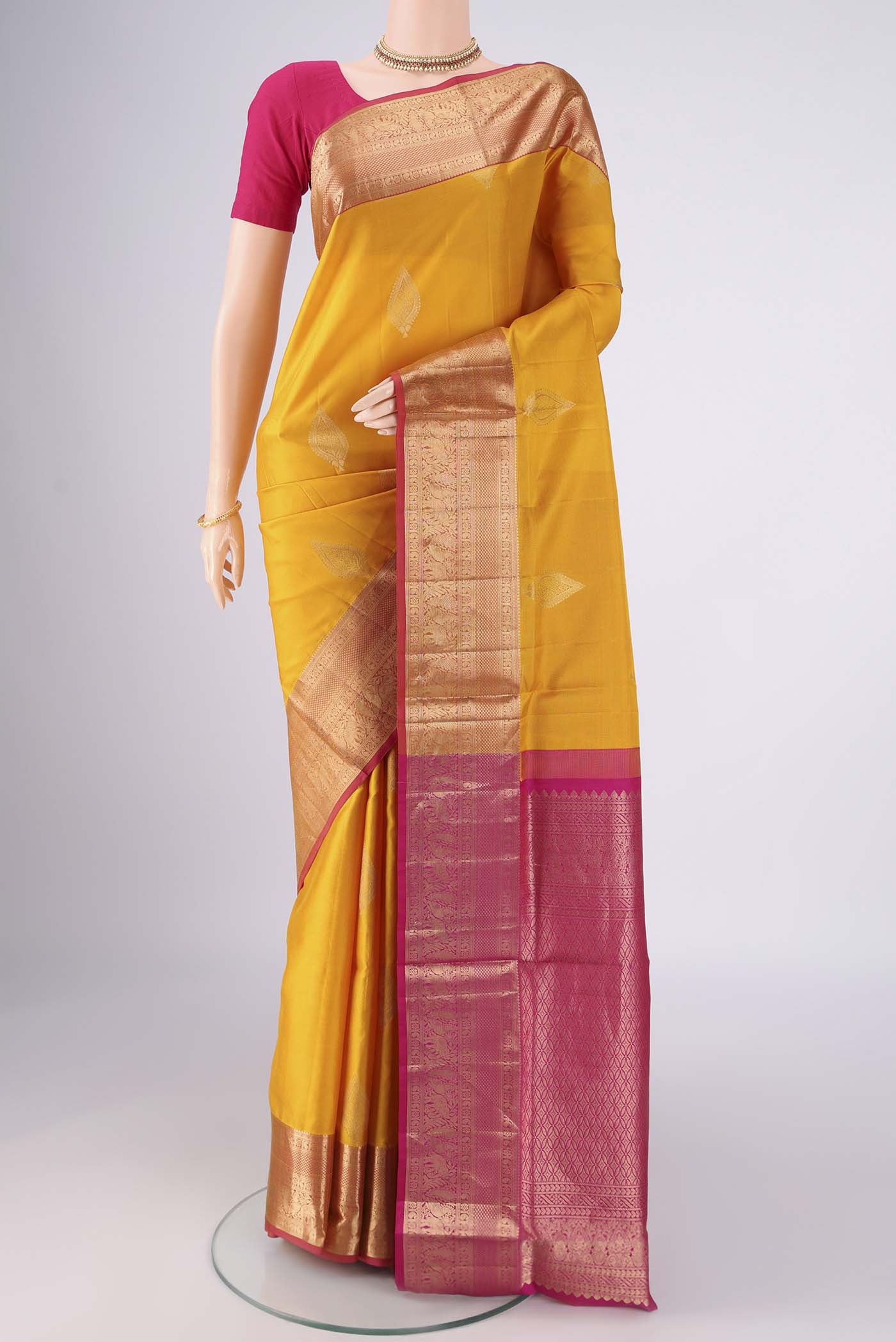 Yellow Soft Silk Saree with Zari Butta on the body and Zari Border.  displayed on a mannequin